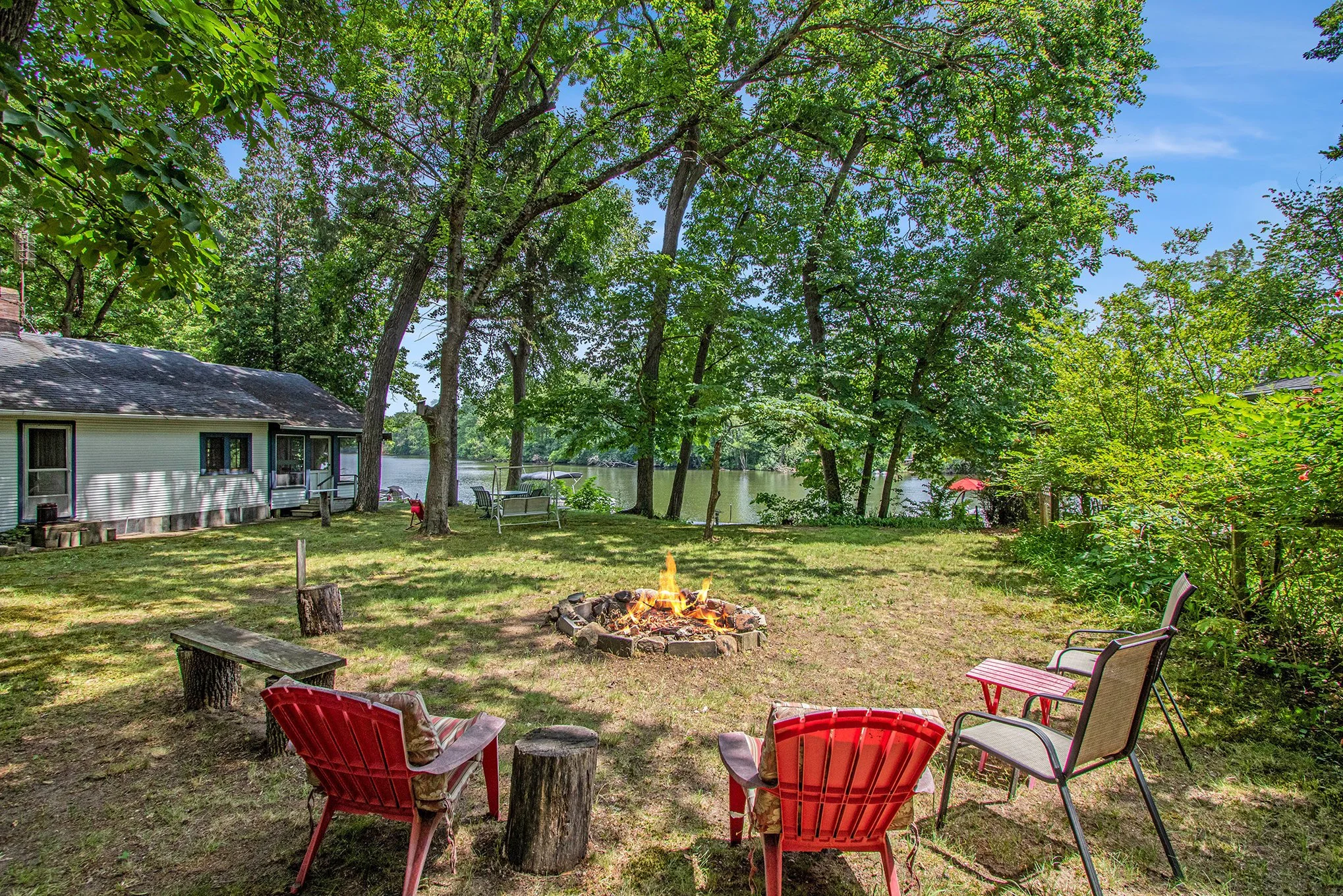 Fire pit and outdoor seating beneath mature trees at 14931 Bachelor Island, a boat-access cottage on the St. Joseph River.