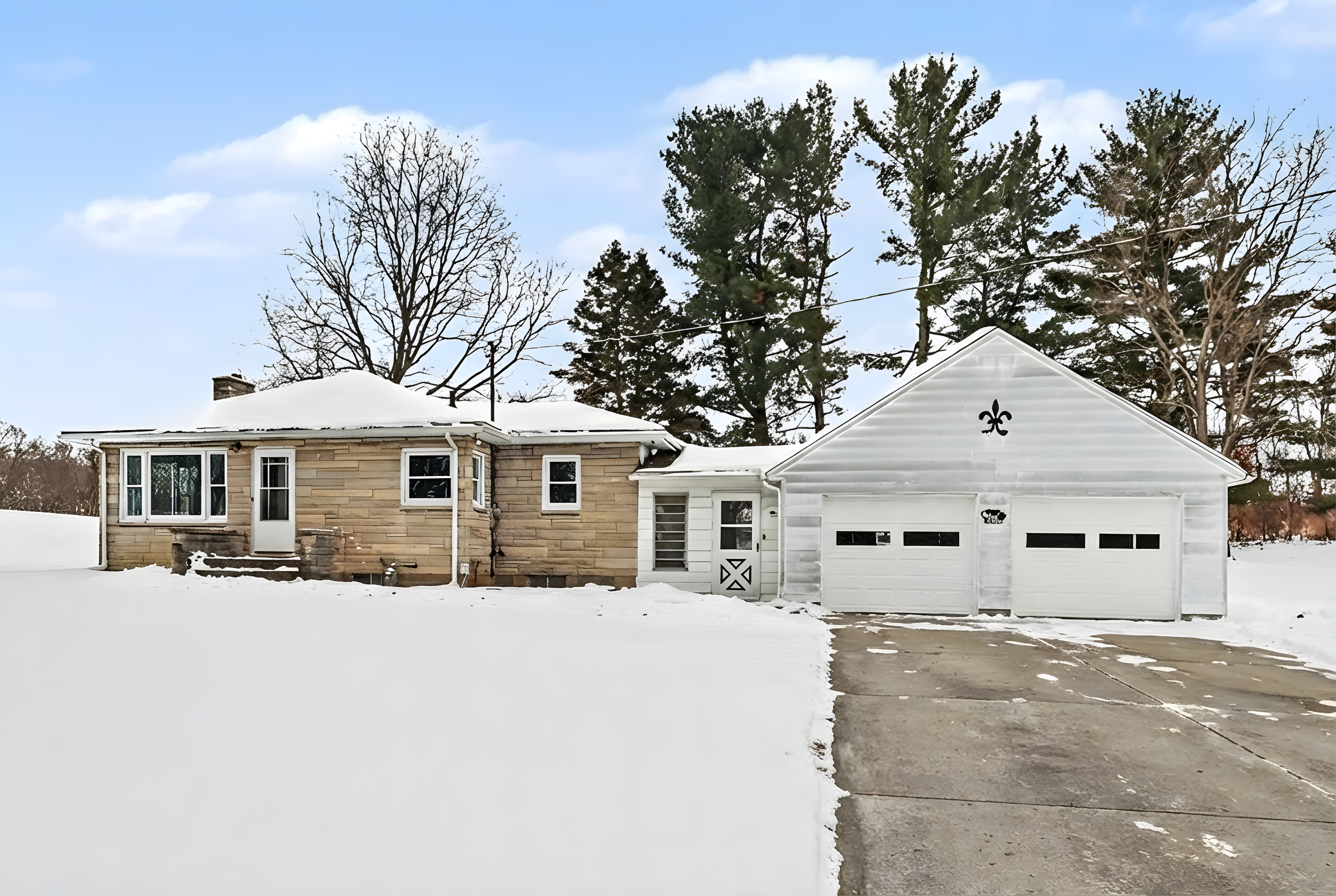 Exterior winter view of 23160 M-78 in Battle Creek, Michigan, featuring a solid stone single-family home on 2 acres with an attached breezeway and white two-car garage in Pennfield Township.