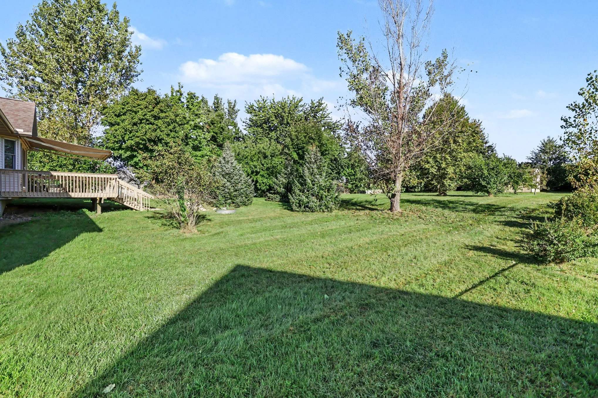 Large fenced backyard at 27420 Birmingham Court in Paw Paw, MI, with mature trees, a spacious lawn, deck, and room for outdoor recreation.