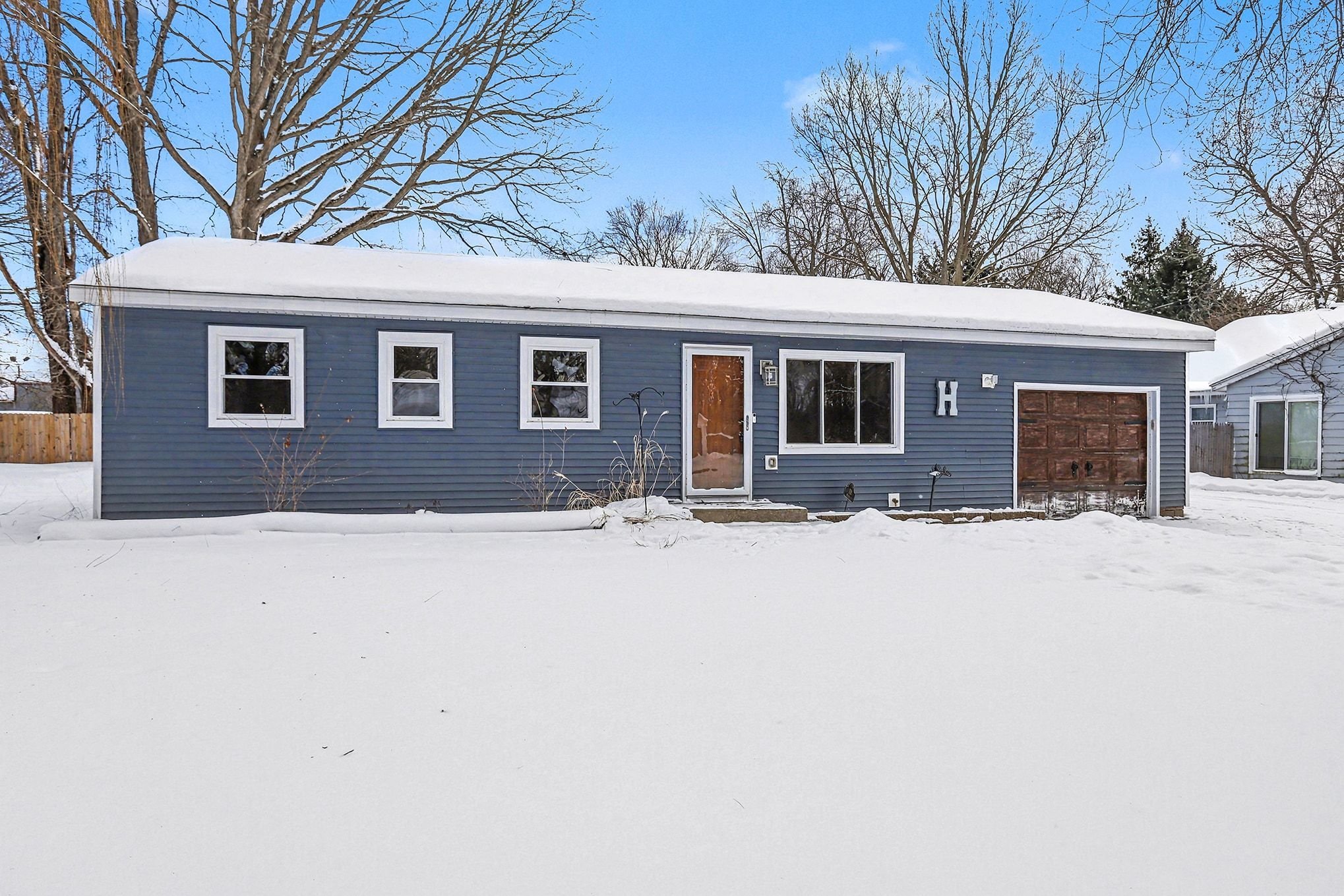 Front exterior of single-story remodeled home at 103 Morrow St in Kalamazoo, MI with blue siding, attached garage, Energy Star windows, and snow-covered yard in winter.
