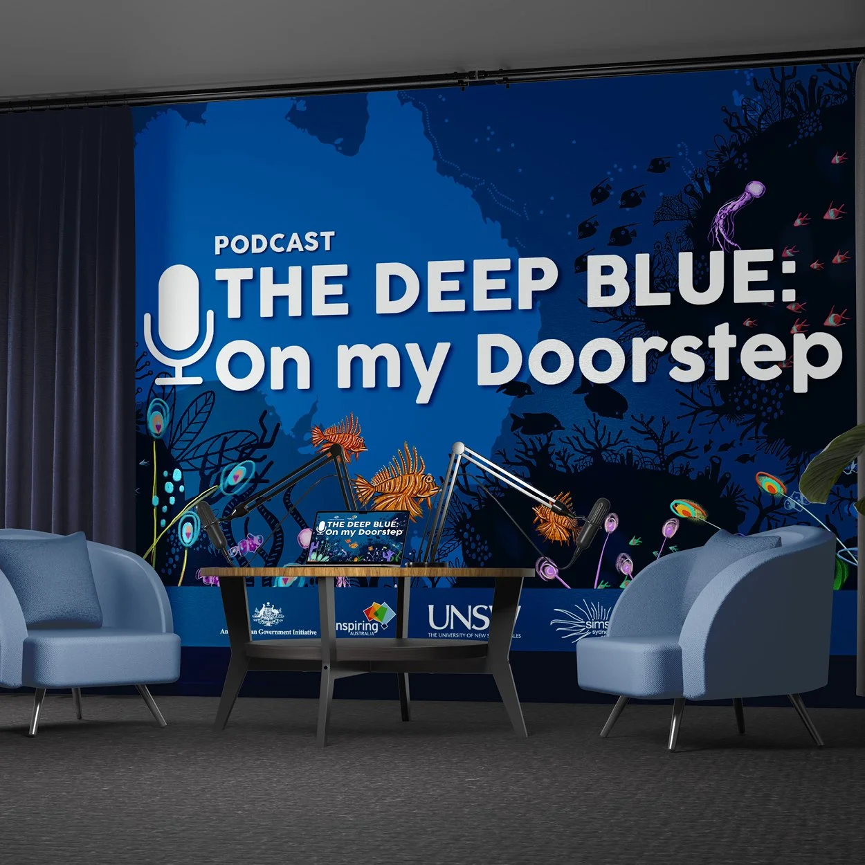 Stage setup for a podcast titled 'The Deep Blue: On my Doorstep' featuring sea life illustrations, microphones, and banners from sponsors including UNSW and Australian Government Initiative.