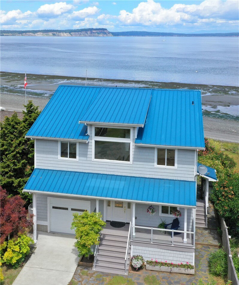  exterior of 2 story house with blue roof and garage on waterfront 