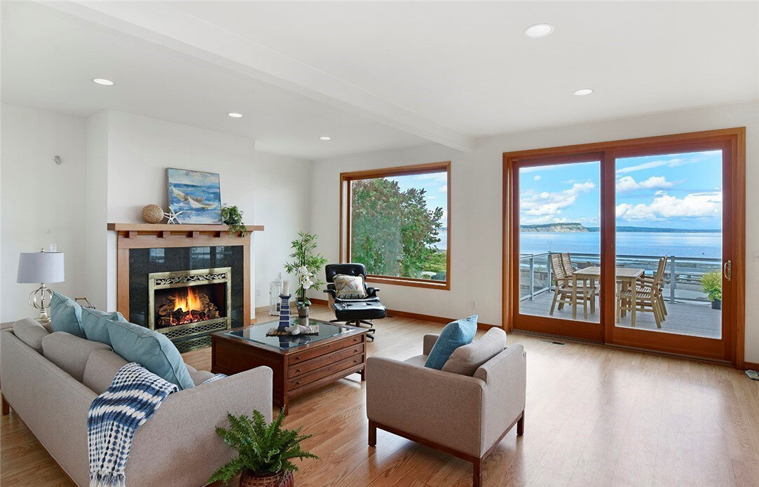  interior of living room with hardwood floors, sliding glass door, window, fireplace, couch and chairs 