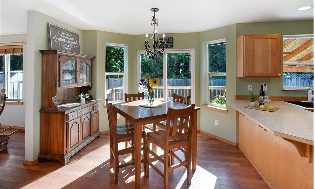  interior of kitchen and dining room with windows, hardwood floors, dining table, and sliding glass door 