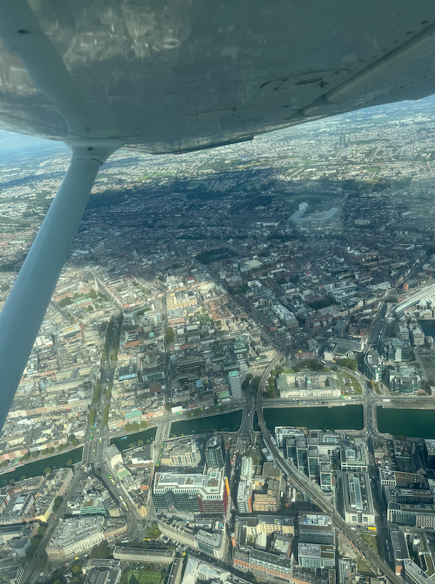 Aerial view of a cityscape with a river running through it, seen from an airplane window.