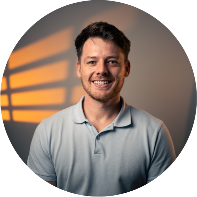 Smiling person with short hair and a light-colored shirt.