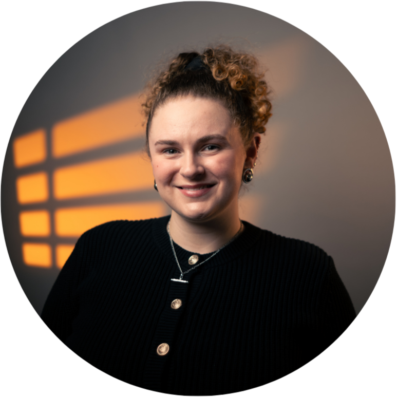 Portrait of a person with curly hair wearing a black outfit against a white background.
