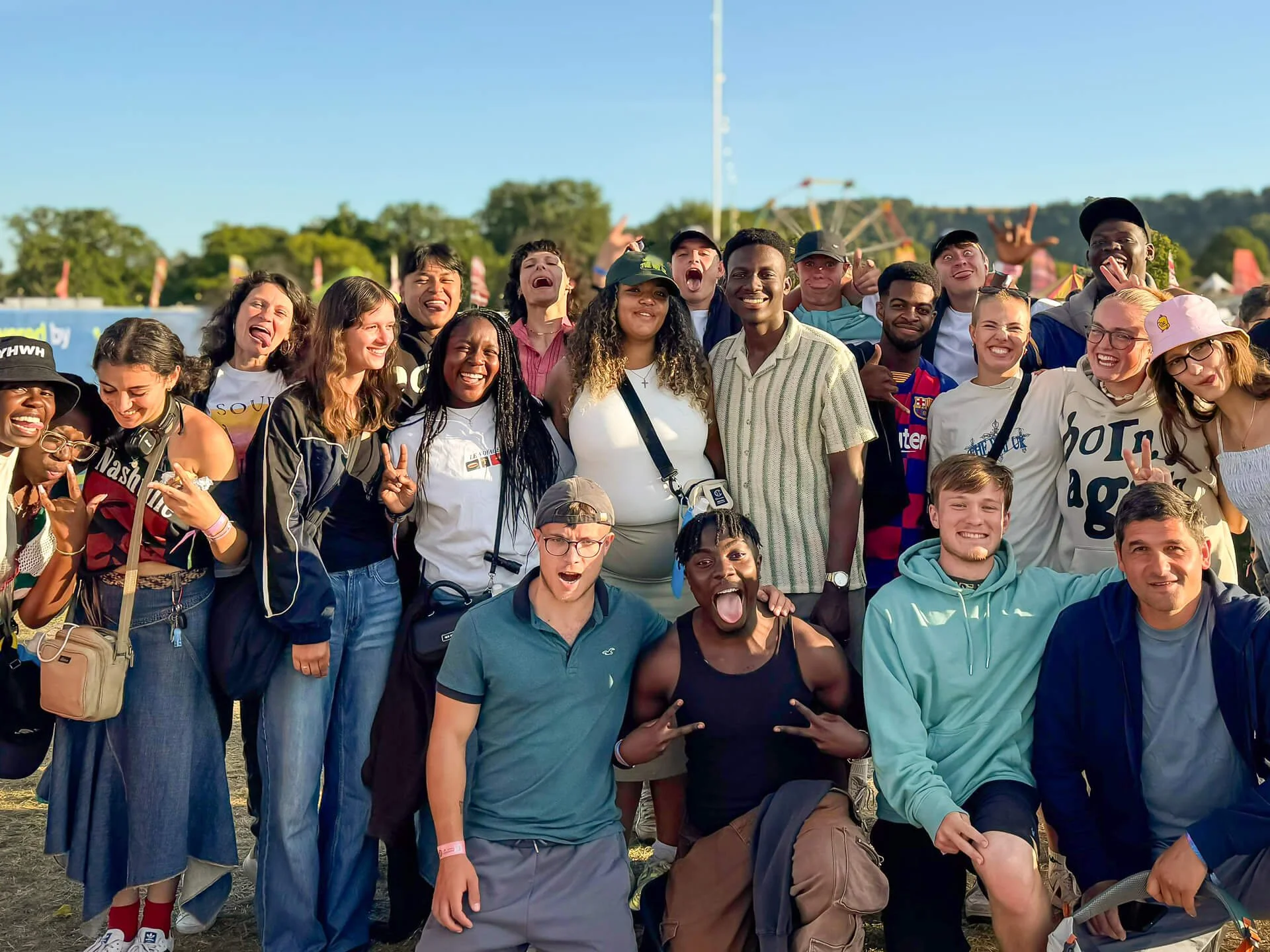 A large, multicultural group of Christian students and young adults gathering at Big Church Fest—a Christian music festival—smiling, laughing, and pulling silly faces at the camera together.