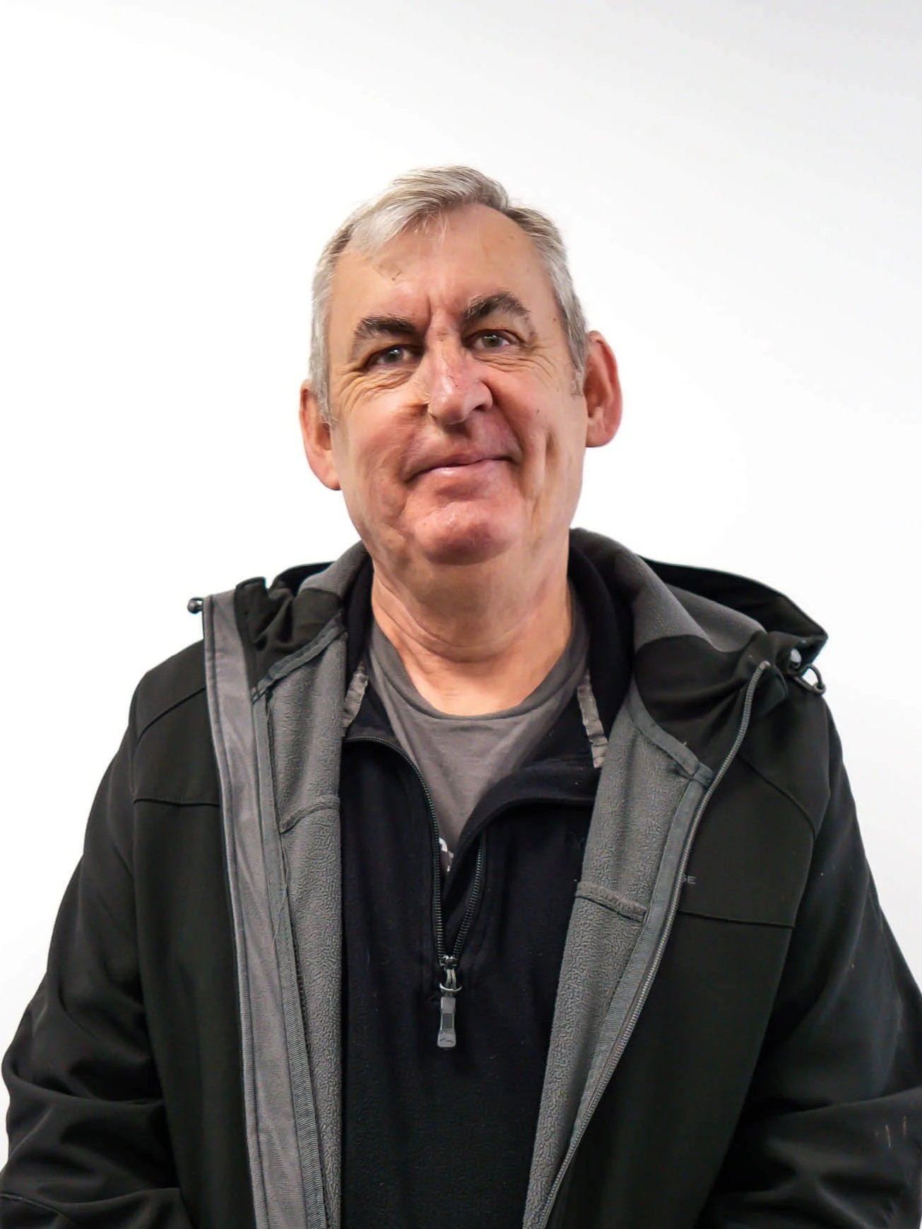 Middle-aged man wearing a black jacket against a white background.
