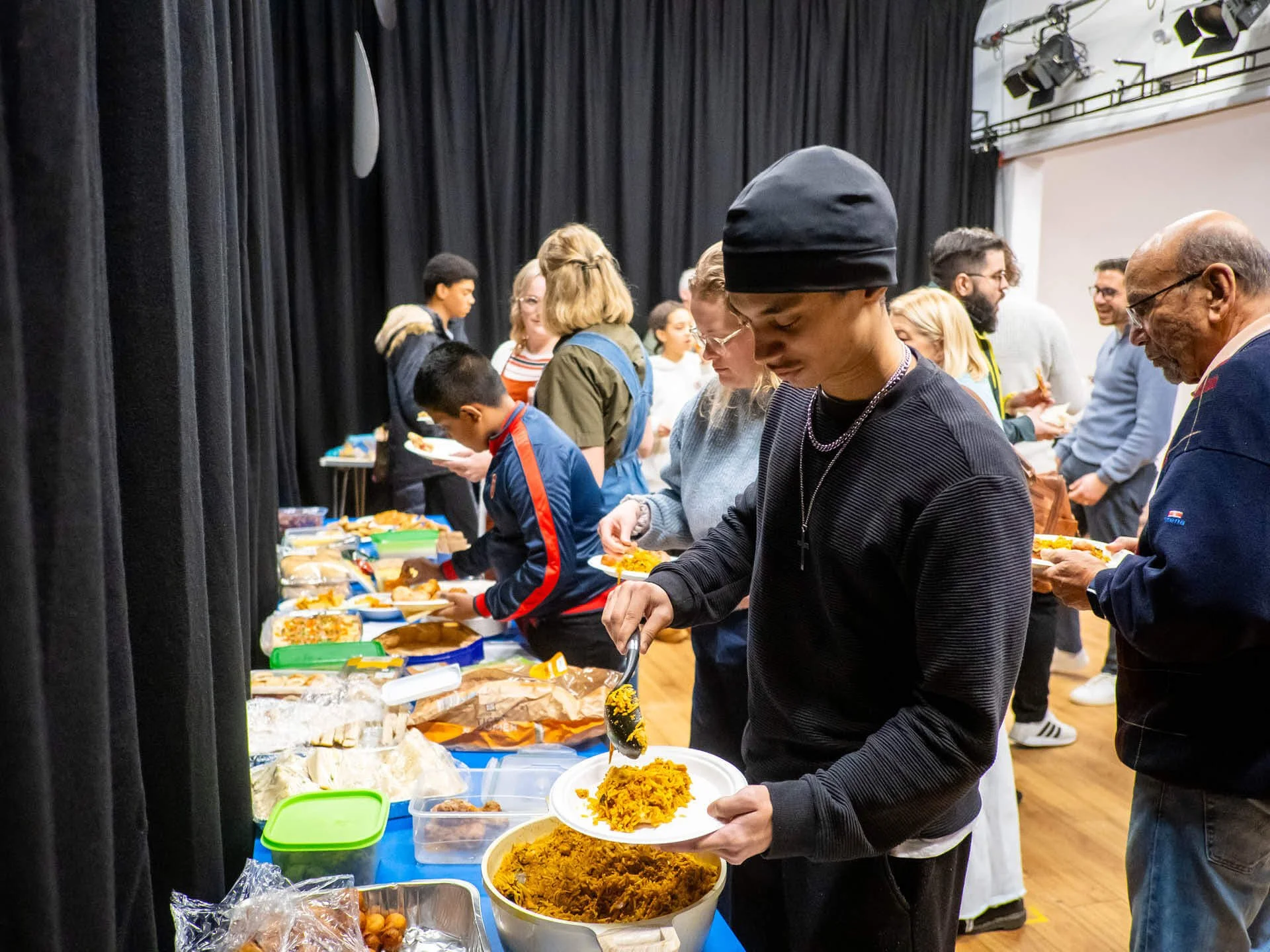 A young man wearing black serves himself rice at a church community lunch.
