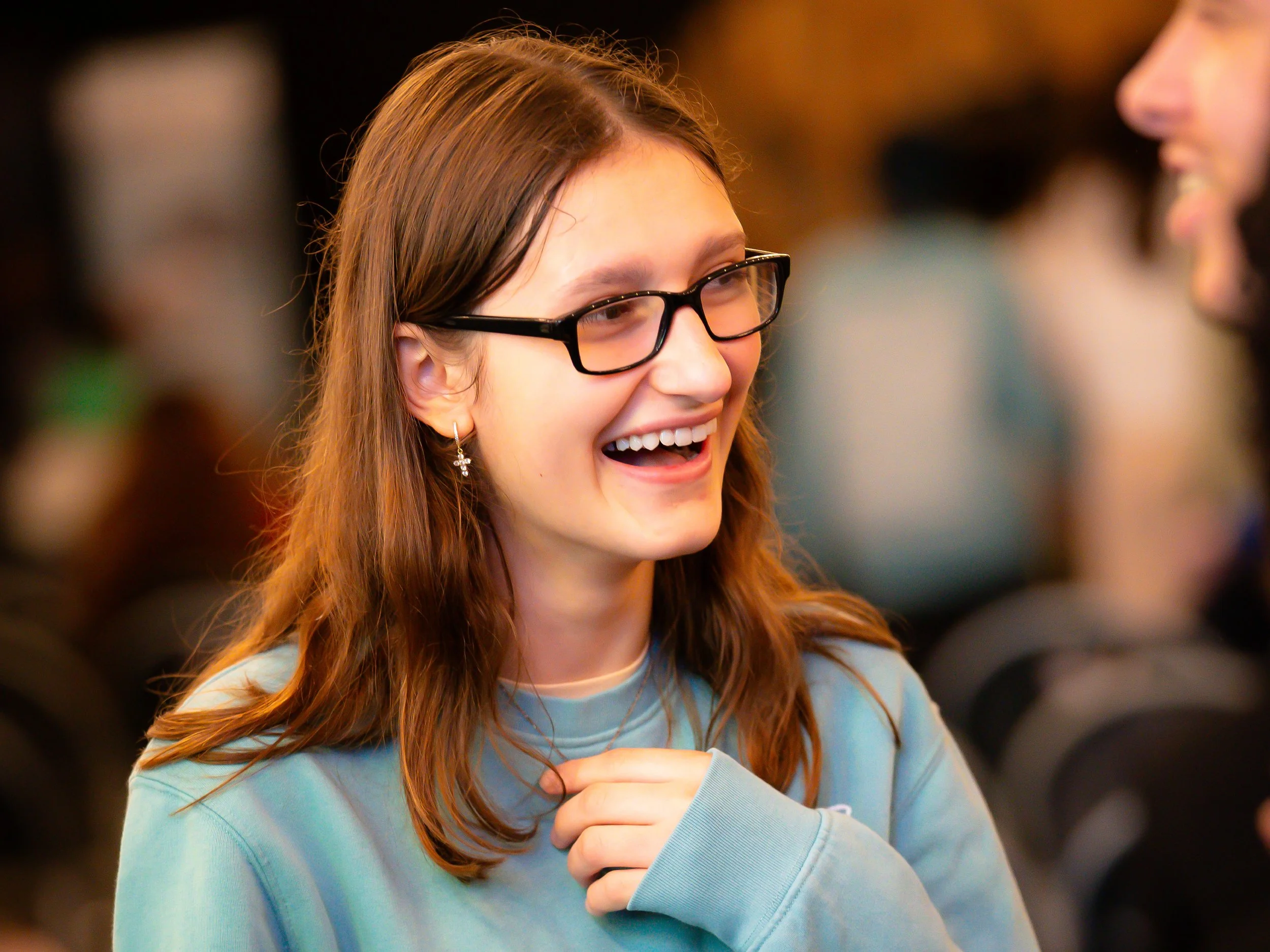 A young Christian girl in her twenties, laughing as she chats to her friends at church.