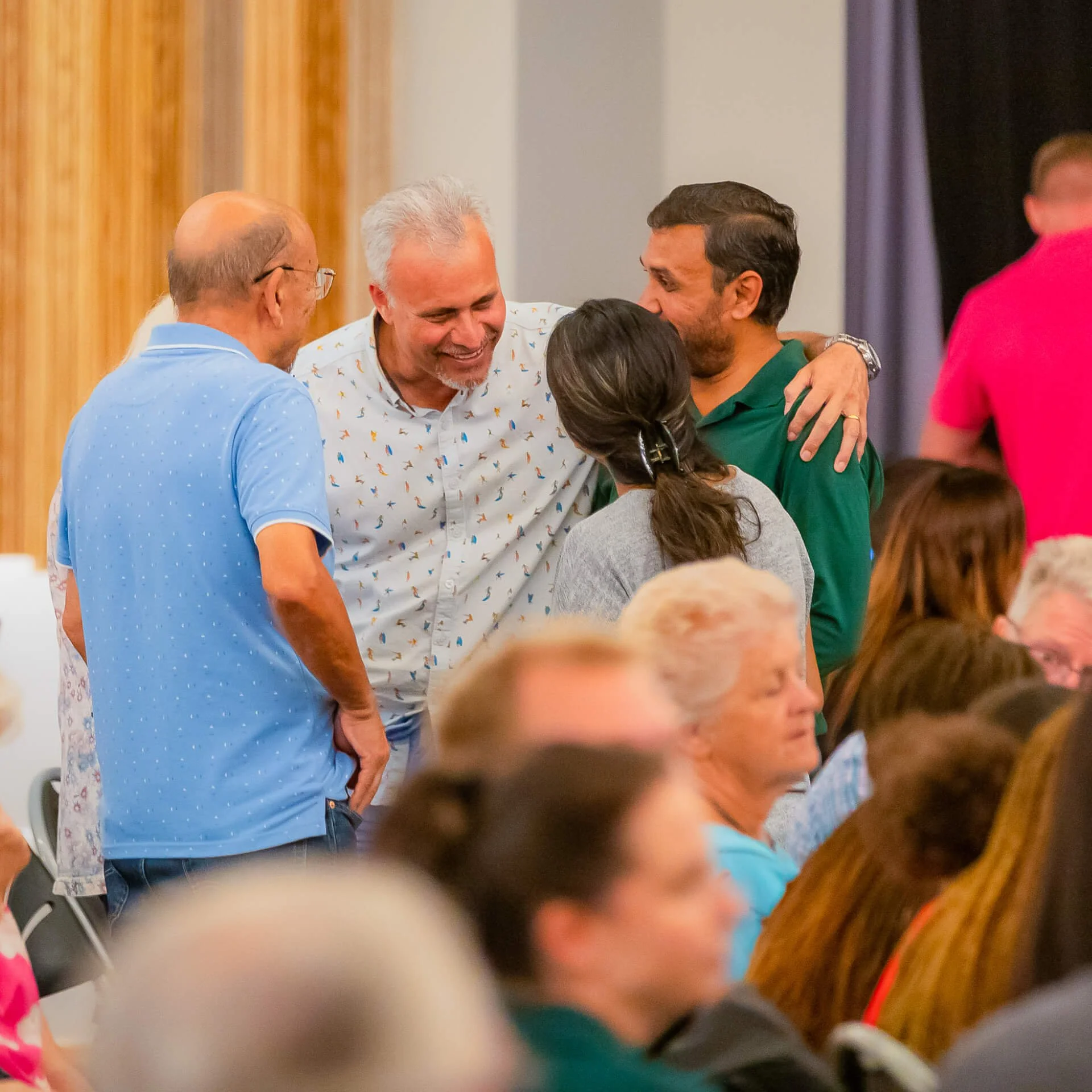A family at church, smiling with their arms around each other, loving and supporting one another.