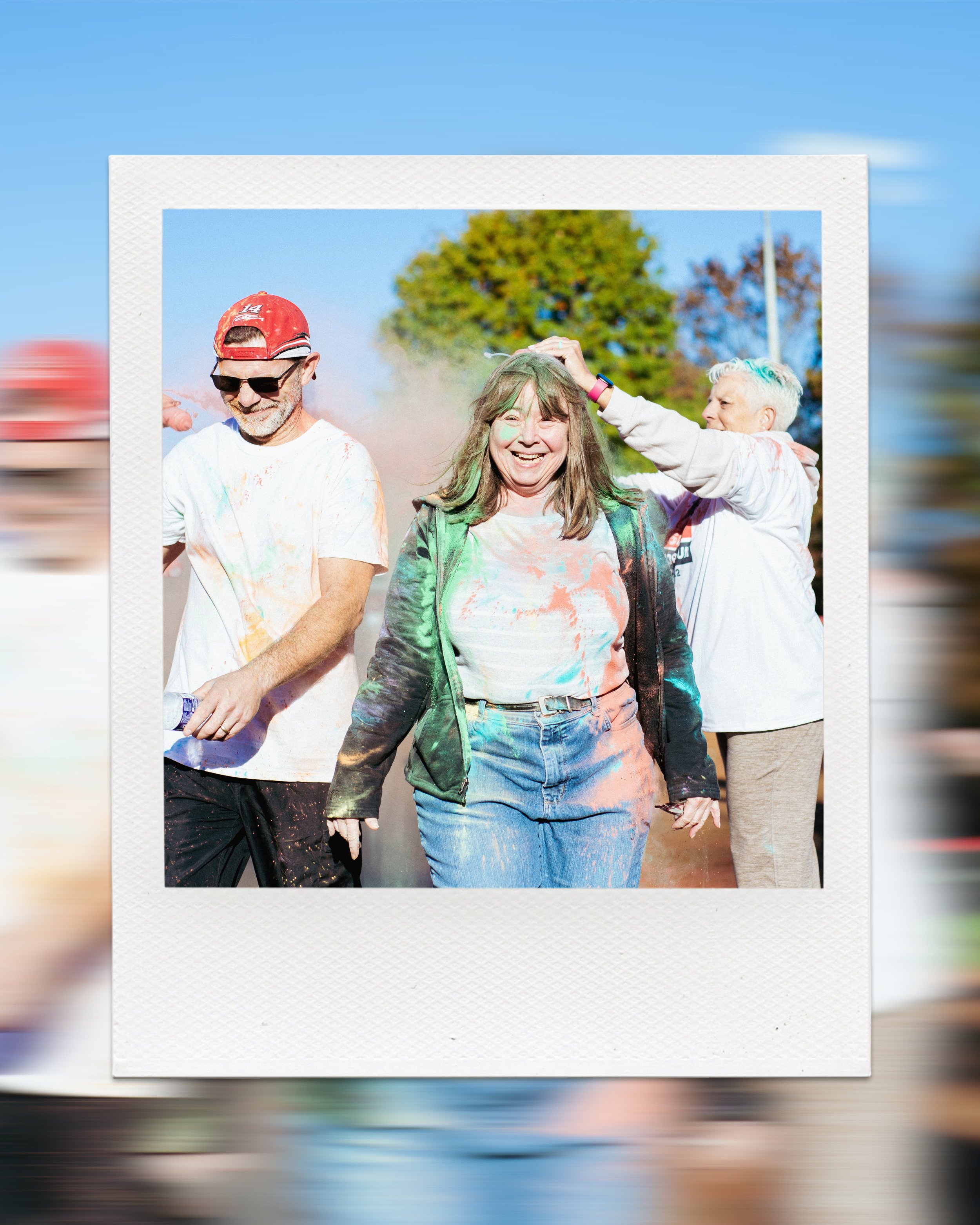 Group of people participating in a color run event with colorful powder on their clothes and faces.