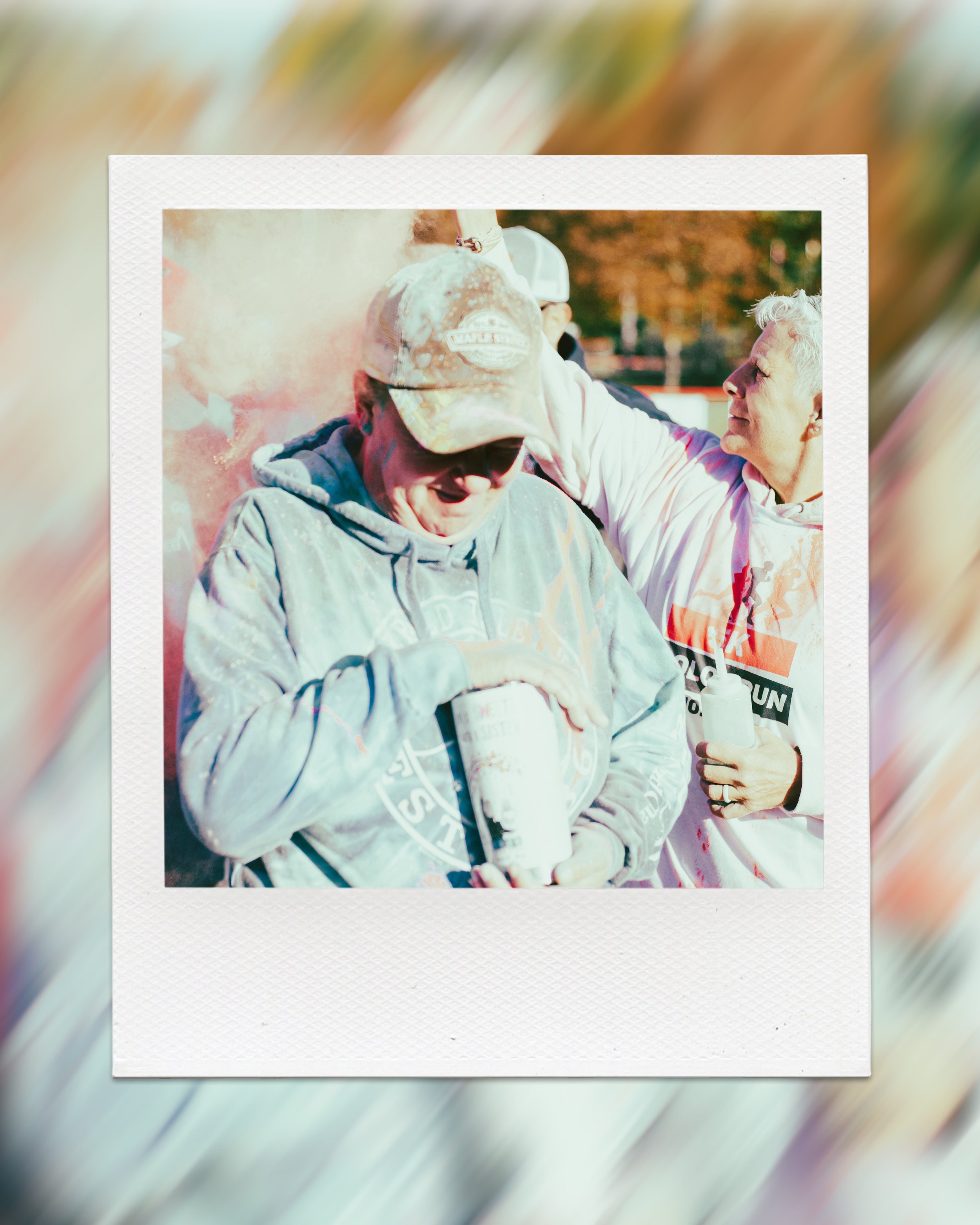 People participating in a color festival or fun run, with colorful powder in the air and casual clothing.