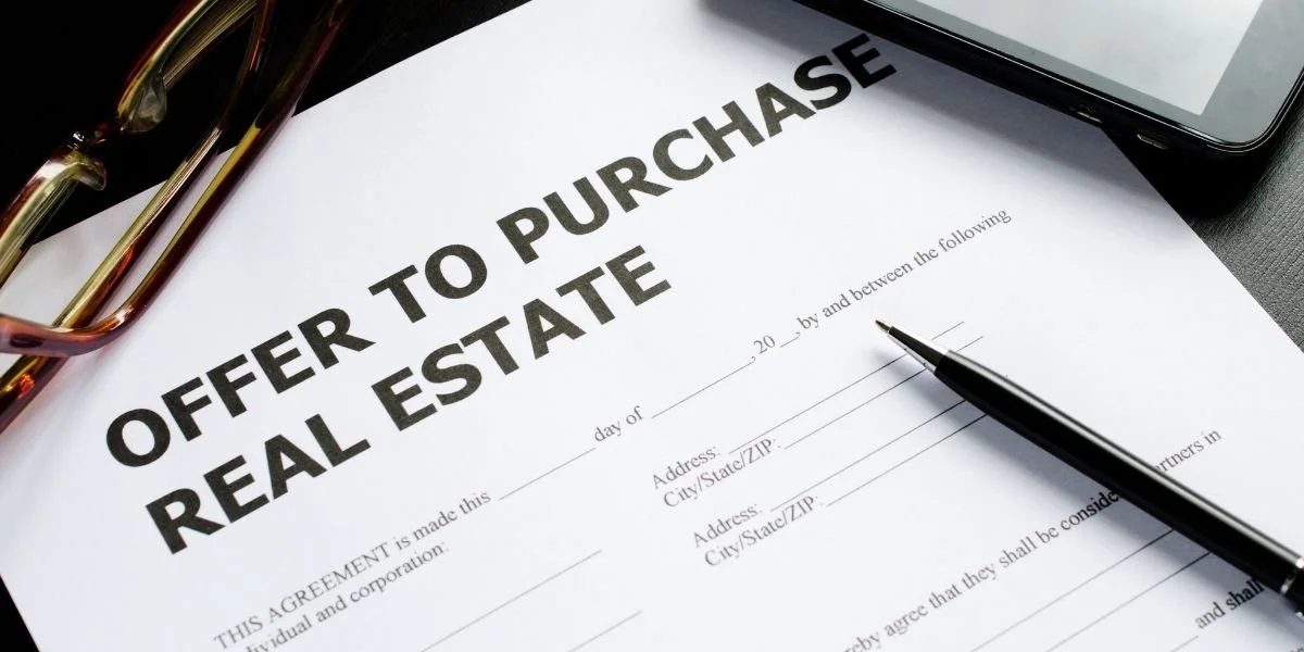 Real estate purchase agreement with a pen, glasses, and tablet, representing residential and commercial property transactions.