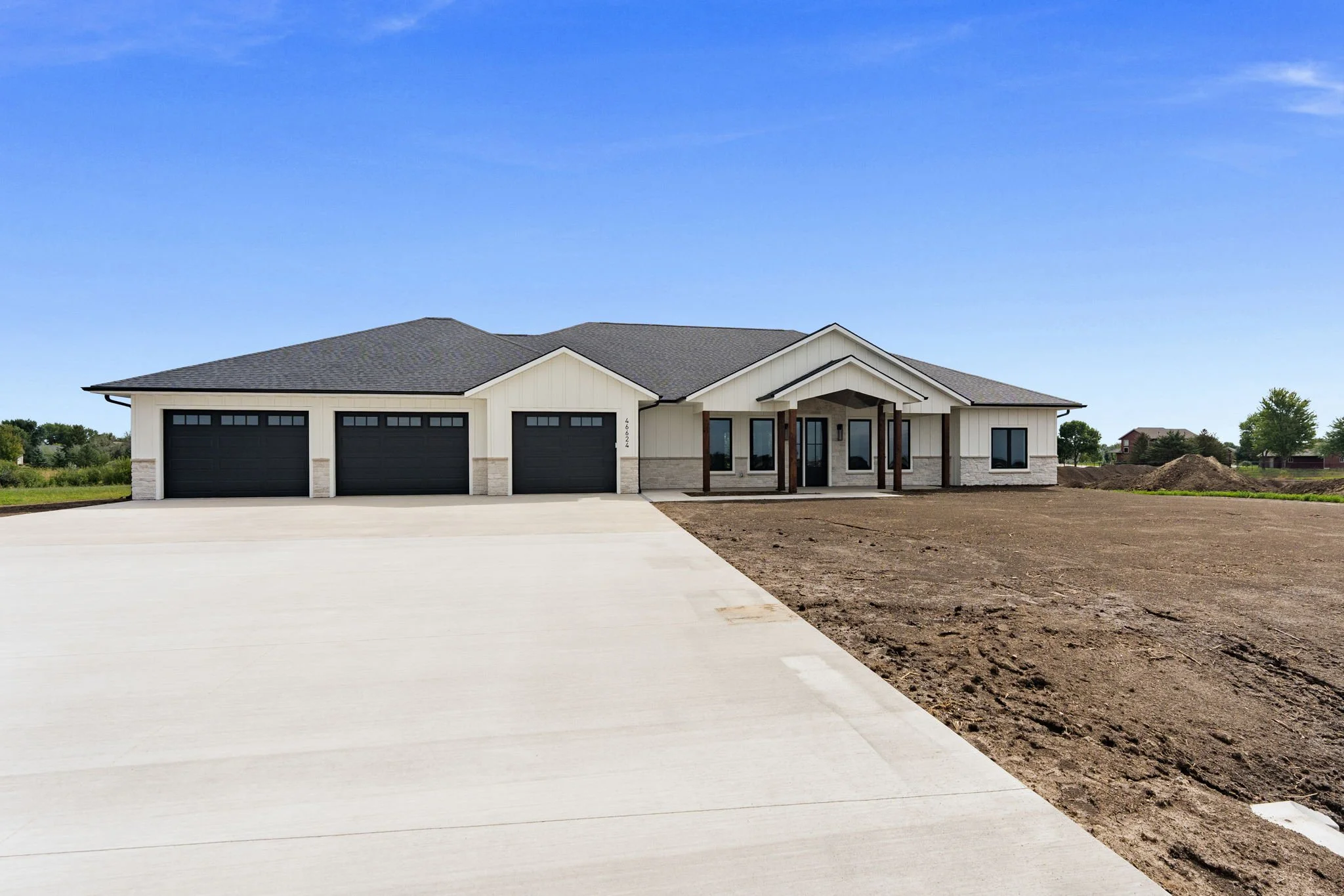 New house with a paved driveway, front yard, and blue sky.