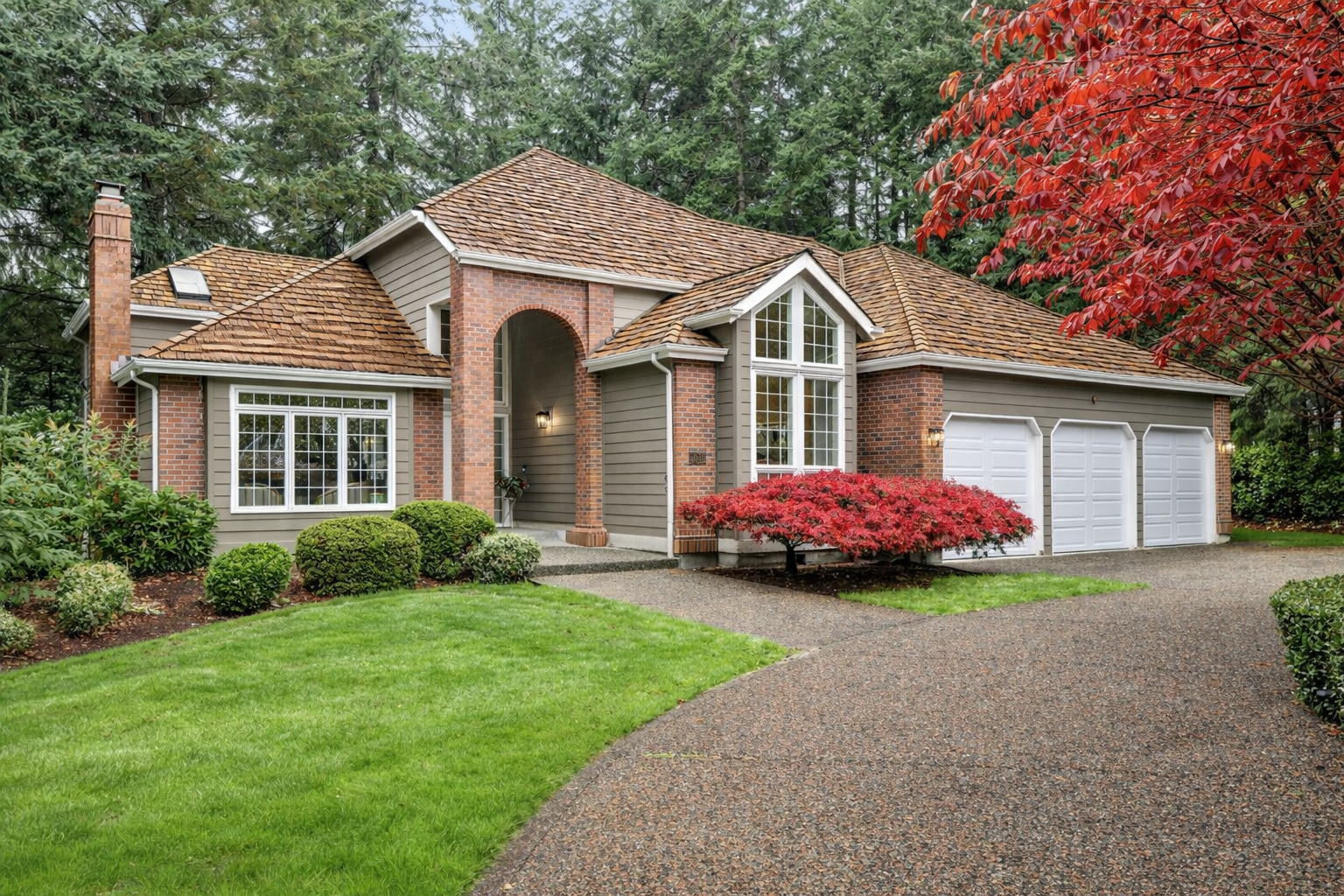 Classic Gig Harbor brick home surrounded by mature Pacific Northwest trees and manicured landscaping. Exactly the kind of property covered in Stacia's home buyers guide