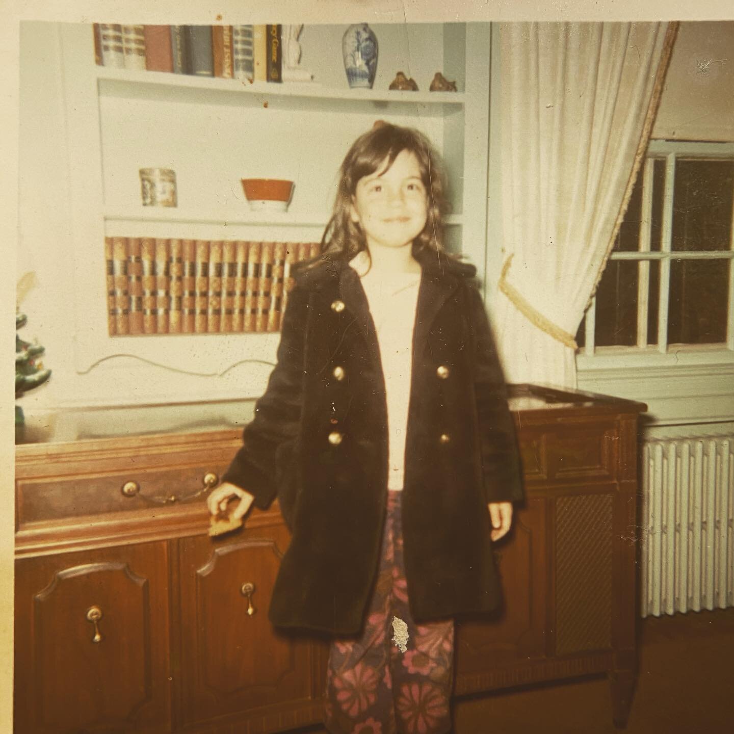 badass ragamuffin eating coffee cake in a chilly New England living room thus wearing a coat in front of the stereo console which is undoubtedly playing the Godspell soundtrack at age just about to turn 7.