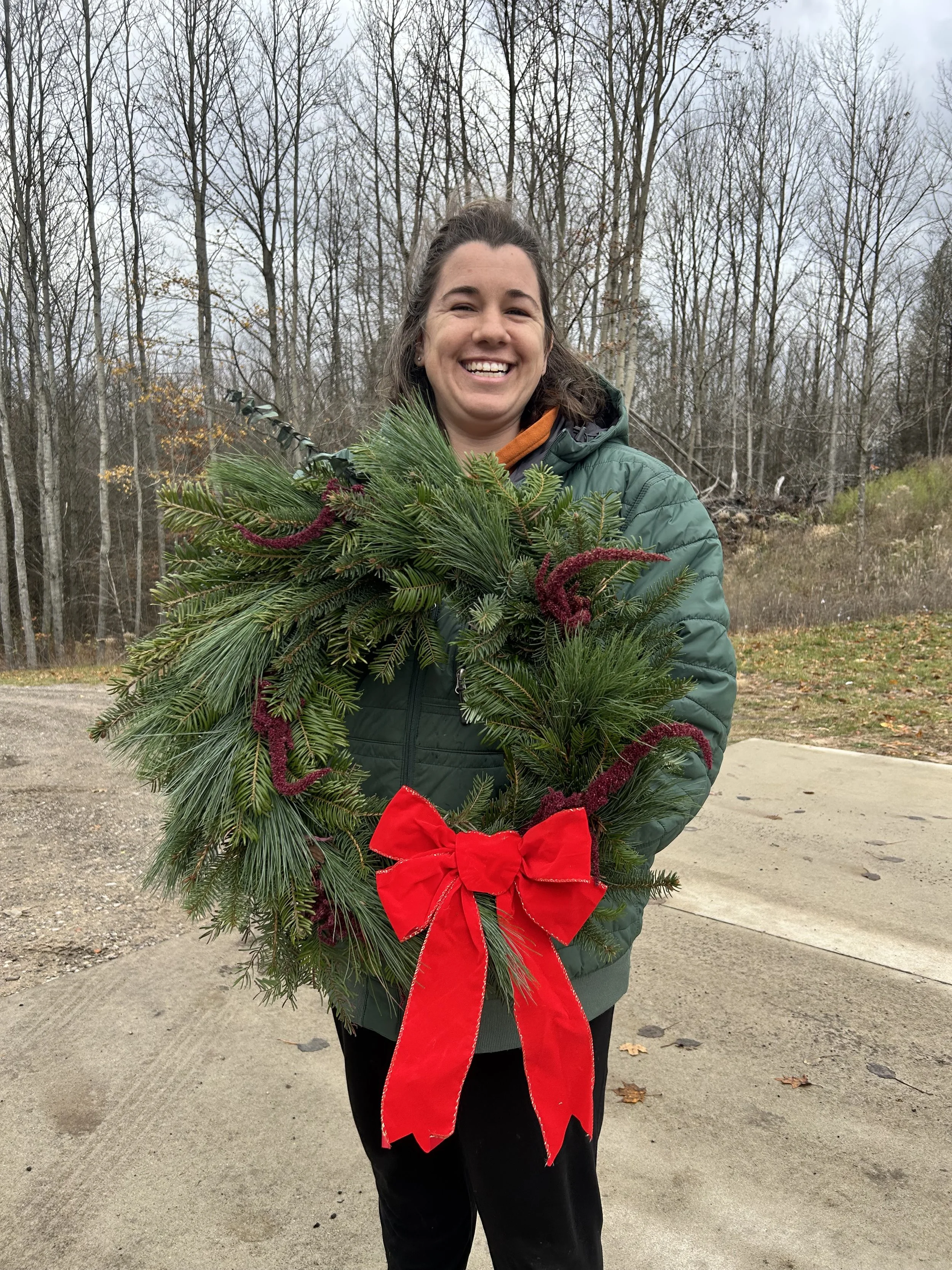 Nicole Mezeske holding a holiday wreath with a big red bow