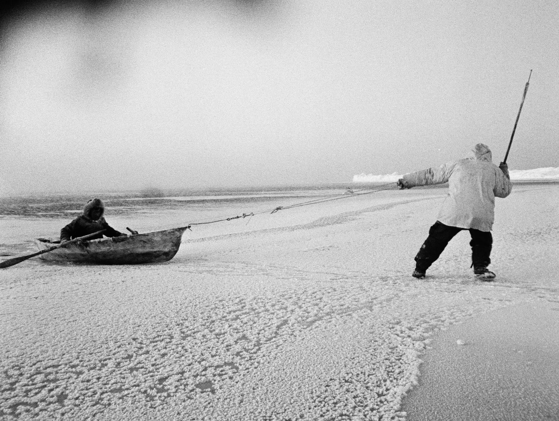 A hunter pulling his companion over thin ice. The umiaqalrulaq (skin boat) was used to retrieve a seal shot in open water.
