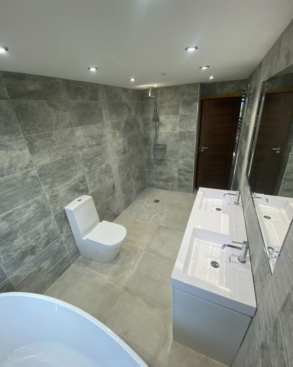 Luxury bathroom previously installed by Cotswold Vale with stunning grey tiling and white suiteg