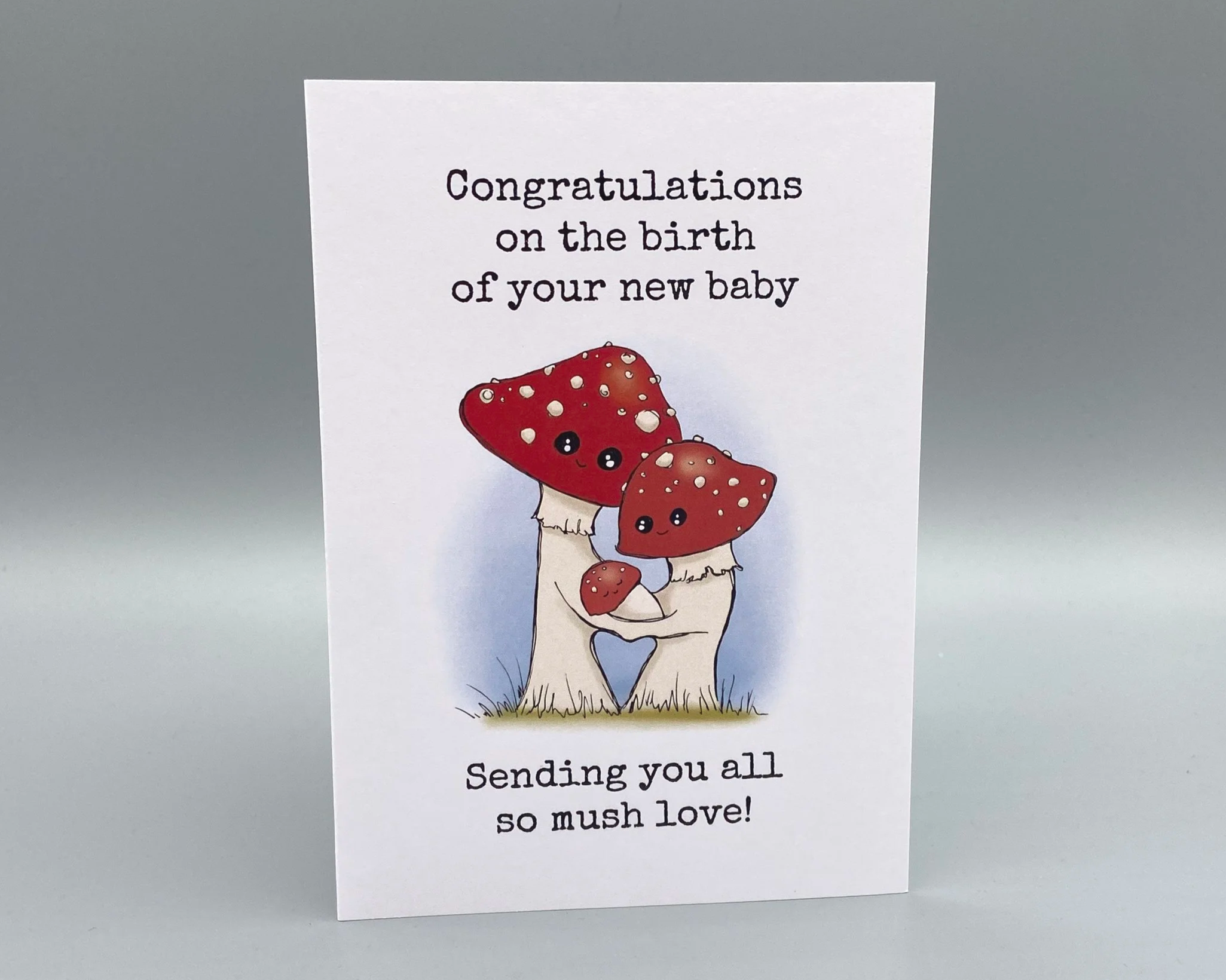 Congratulations on the birth of your new baby greetings card illustrated cute toadstool family with baby. Unisex card for baby boys or baby girls. By Devon artist Helen Leslie Illustrator