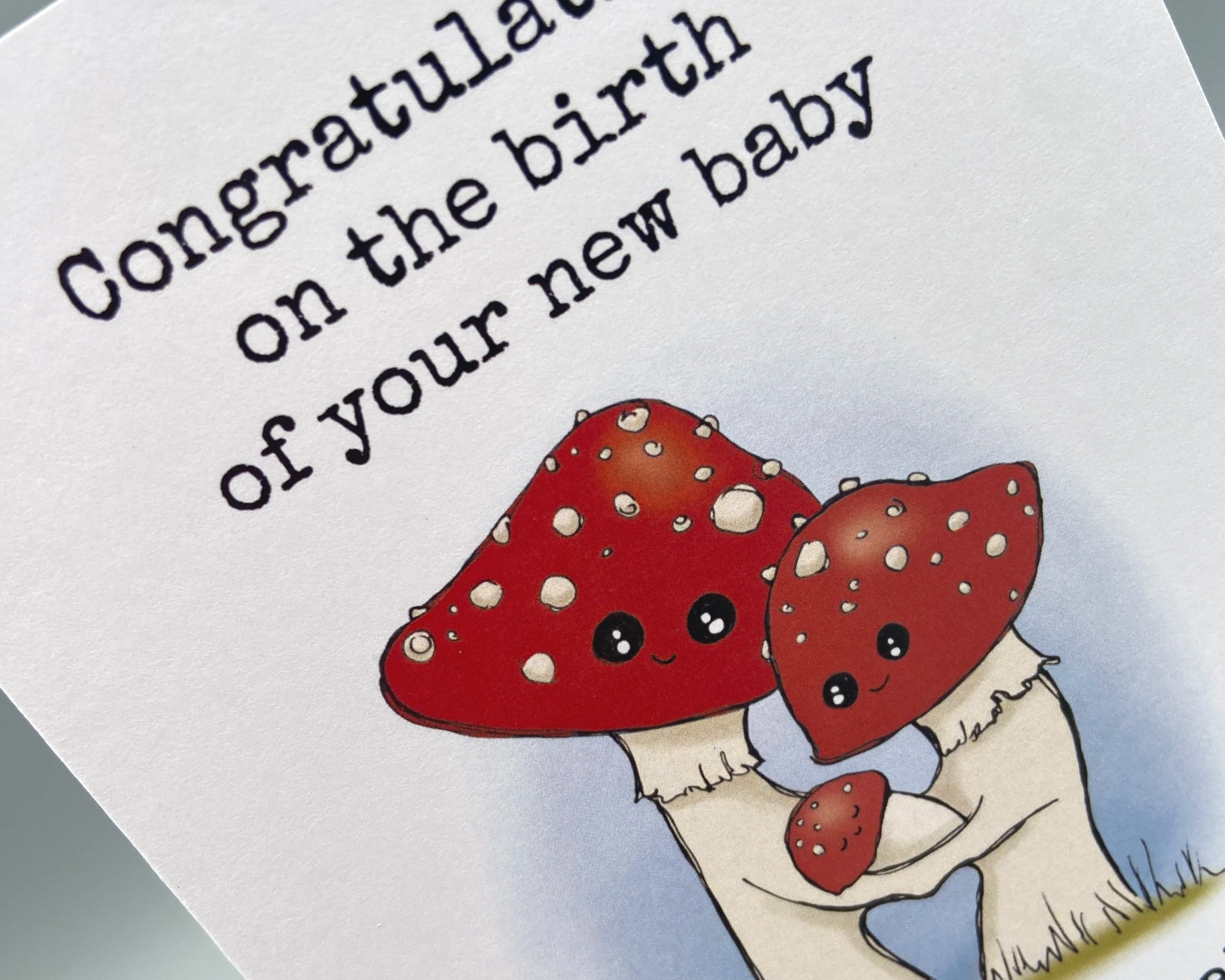 Congratulations on the birth of your new baby greetings card illustrated cute toadstool family with baby. Unisex card for baby boys or baby girls. By Devon artist Helen Leslie Illustrator