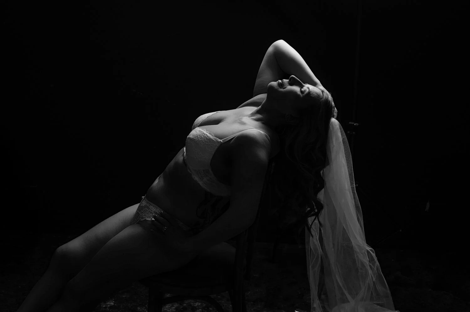 black and white image of woman in veil leaning back on chair 