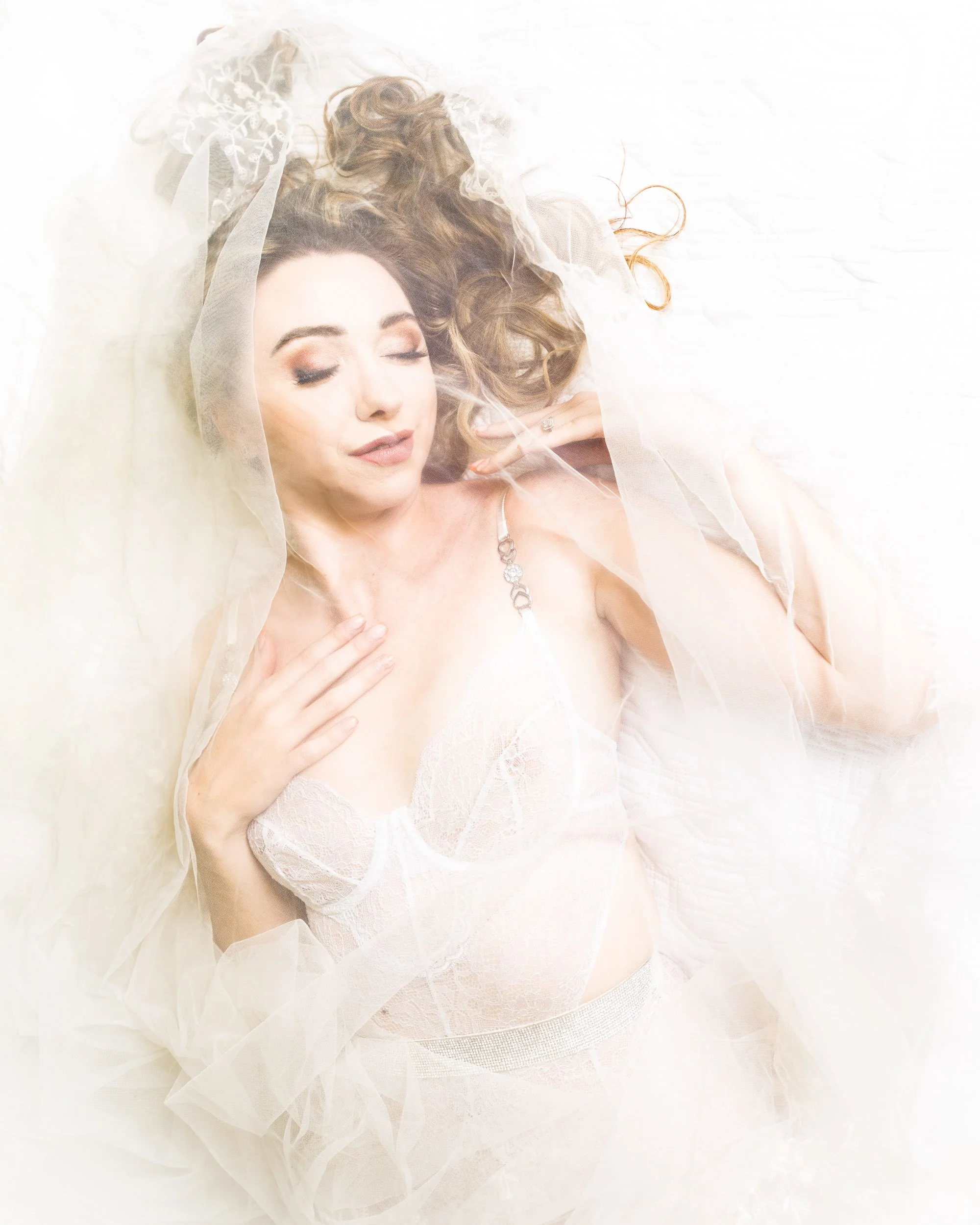 Bridal lingerie with veil in laying down pose