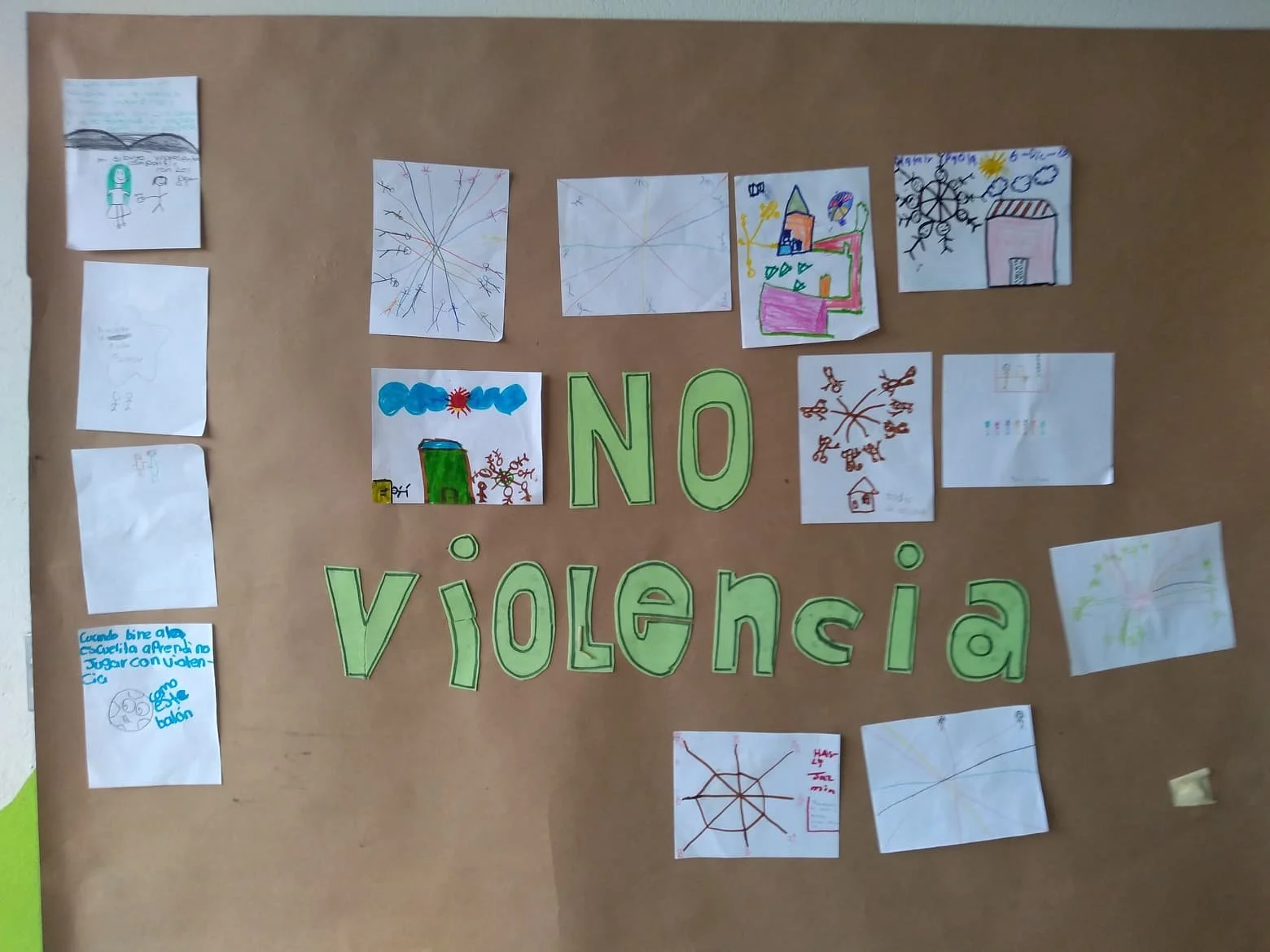 Children's drawings surrounding the phrase 'NO violencia' on a brown bulletin board.