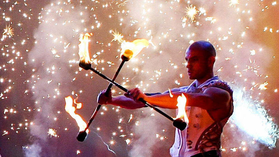Powerful Classical Fire Dancer with Fire Equipment and Stage Pyrotechnic Effect in the Background