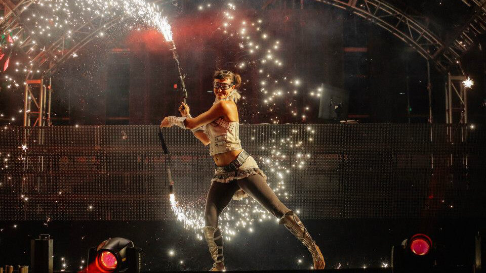 Lachende Tänzerin mit Pyro Xcess Effekt in Händen die Funken auf der ganzen Bühne versprüht, Heineken Festival, Korea