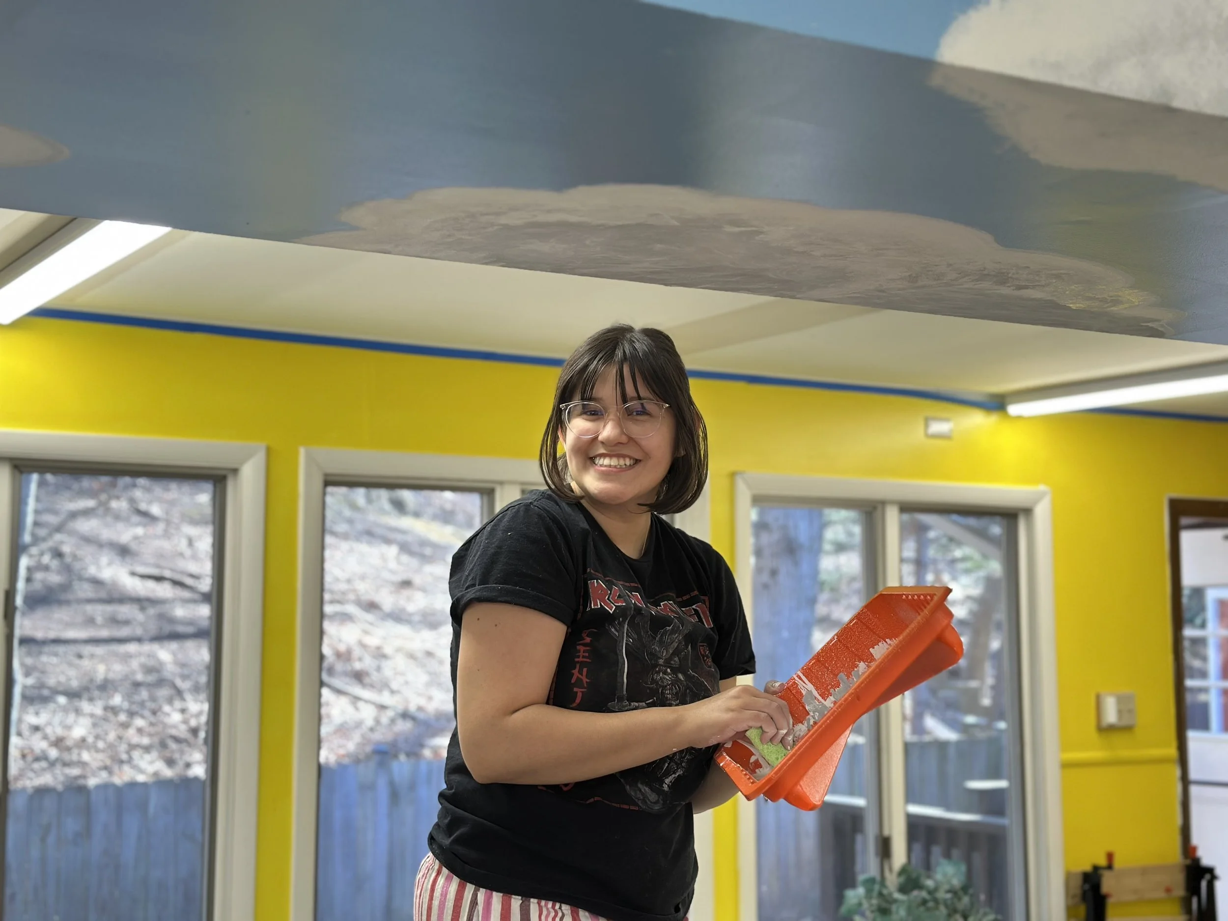 An artist volunteer works with other artists to create a mural in one of the cabin classrooms.