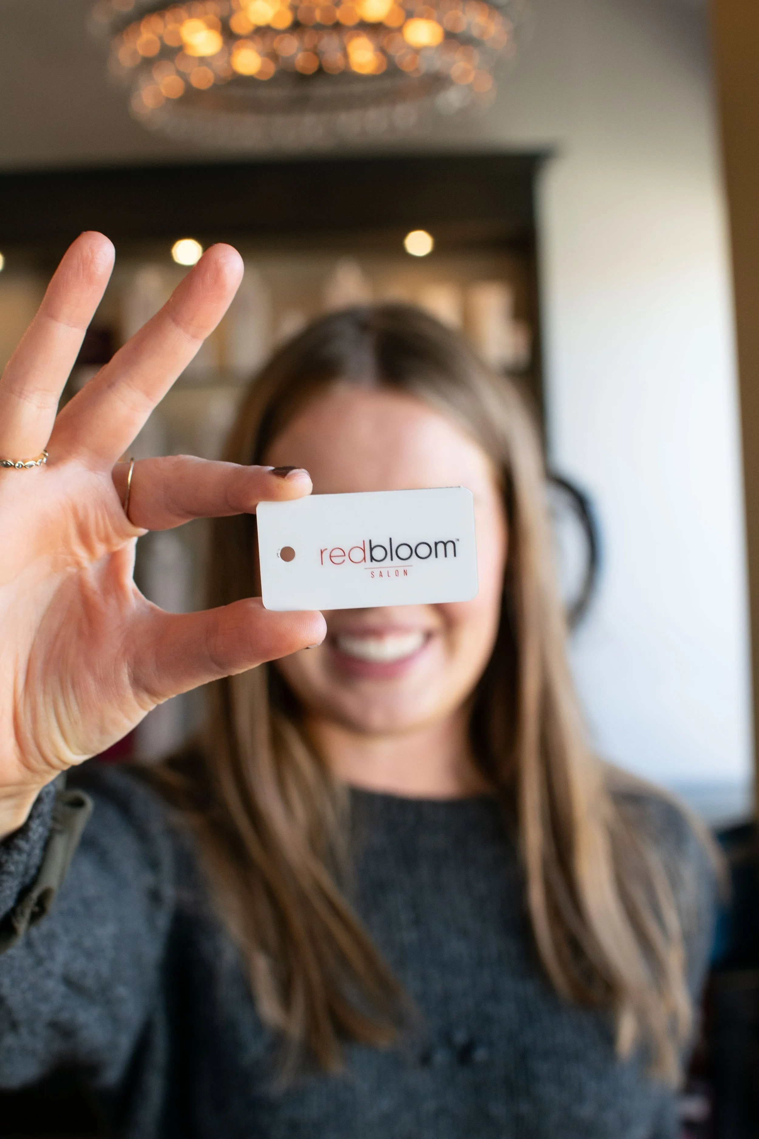 Person holding a card with "redbloom salon" logo.