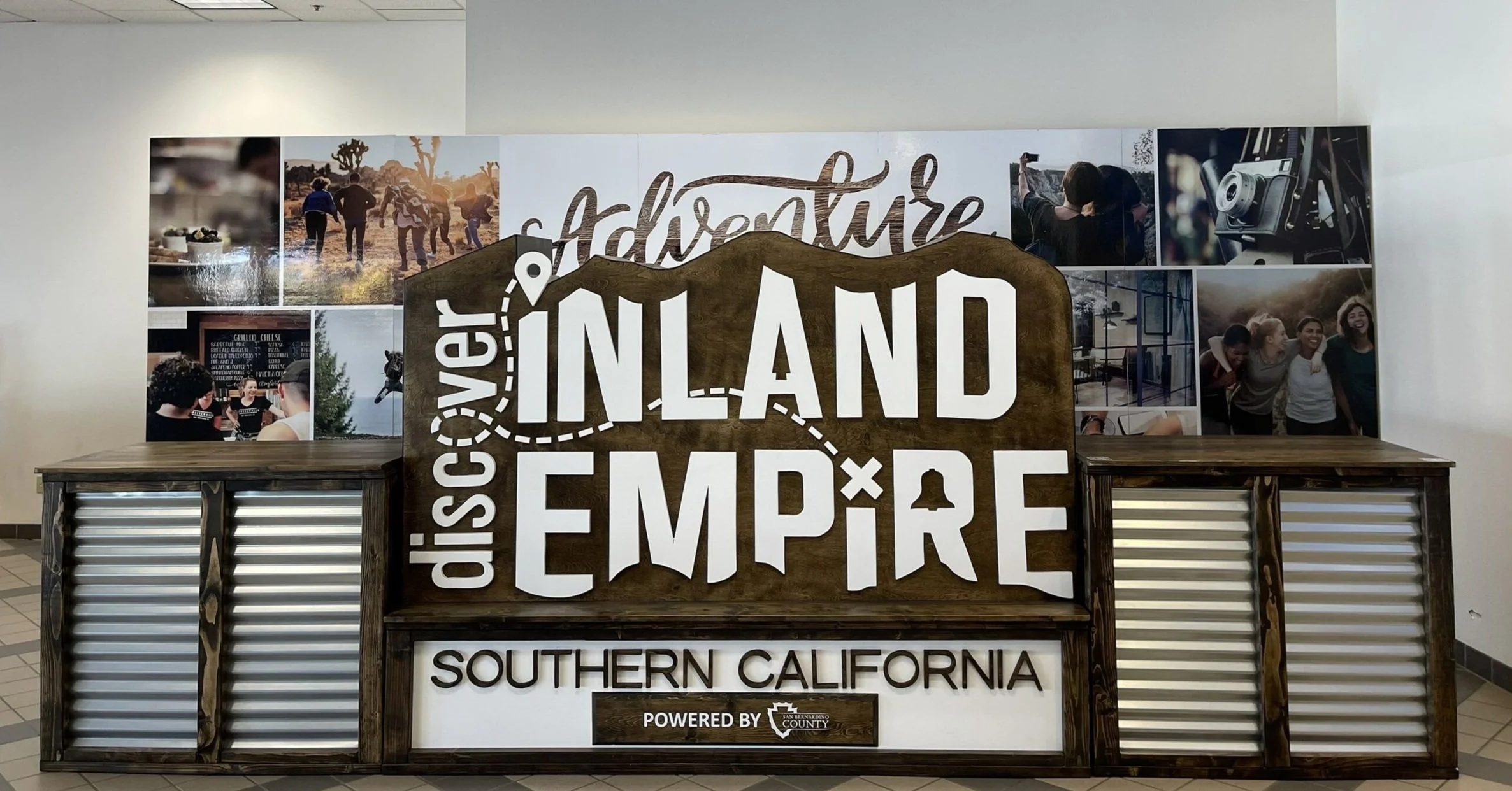 The Discover Inland Empire welcome center display inside ONT's International Terminal, featuring a large branded sign surrounded by destination photography showcasing the region's outdoor adventures, dining, and culture.