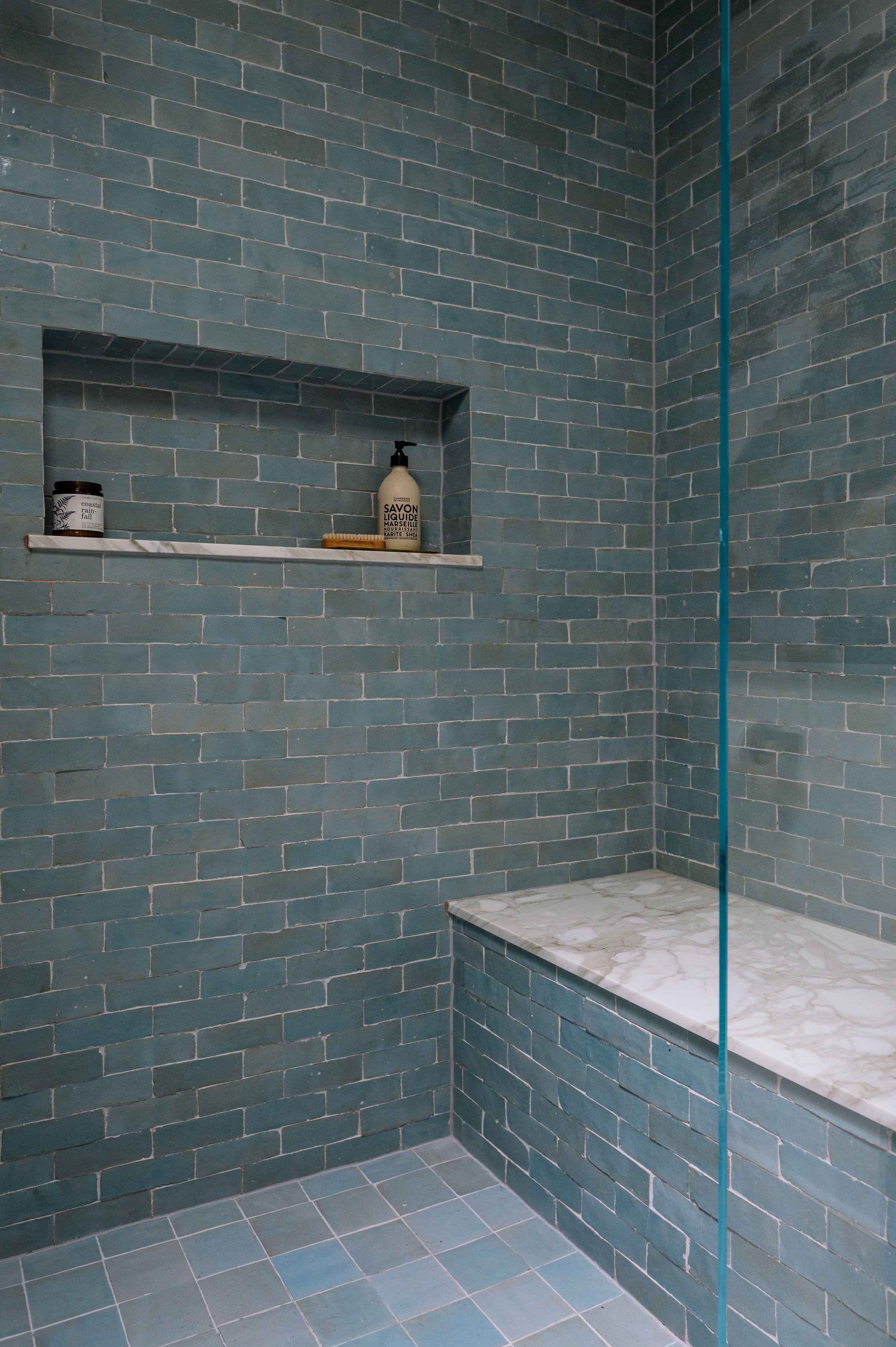 Blue tile walk-in shower with brass fixtures