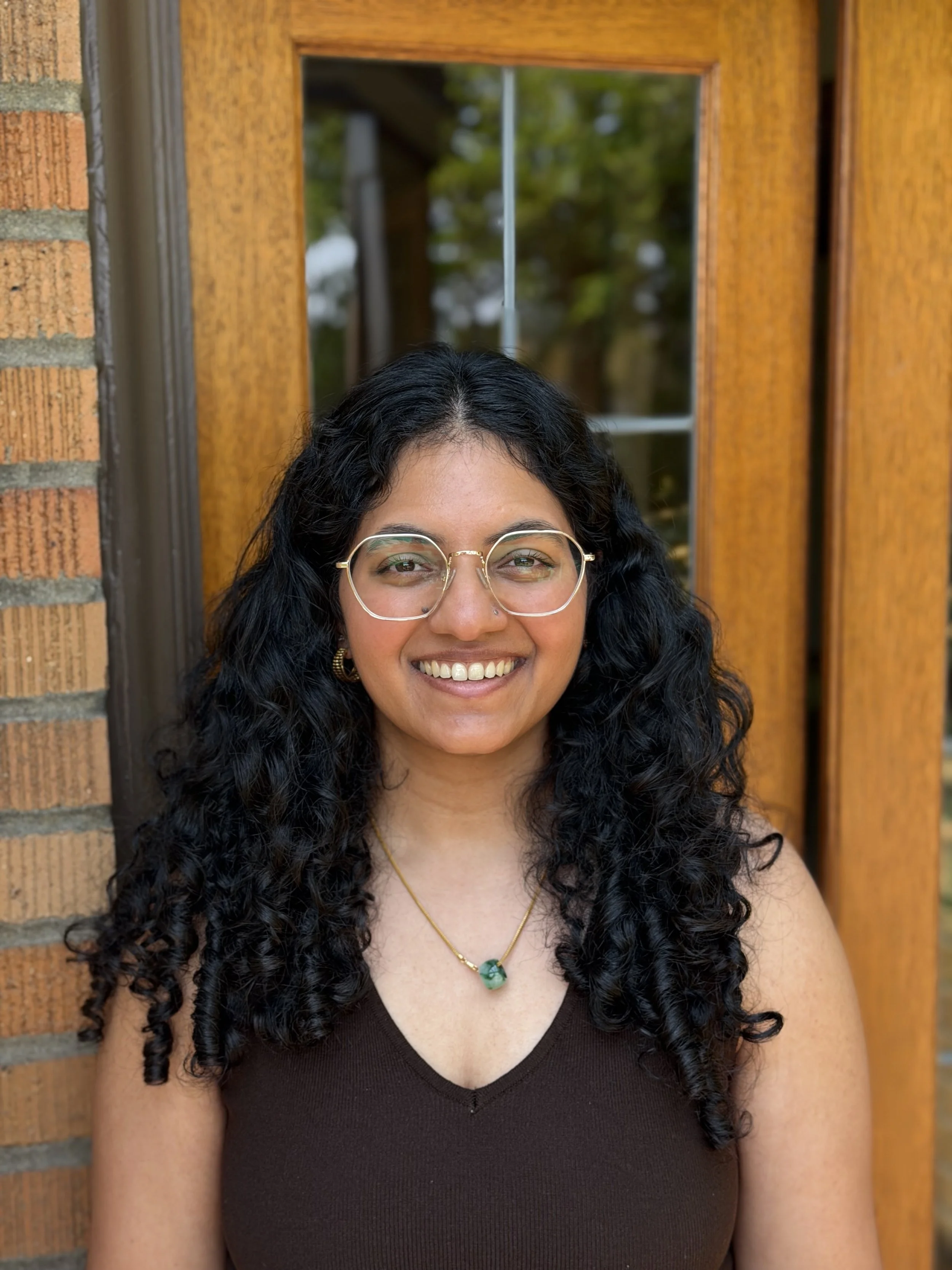 A woman with black curly hair and glasses