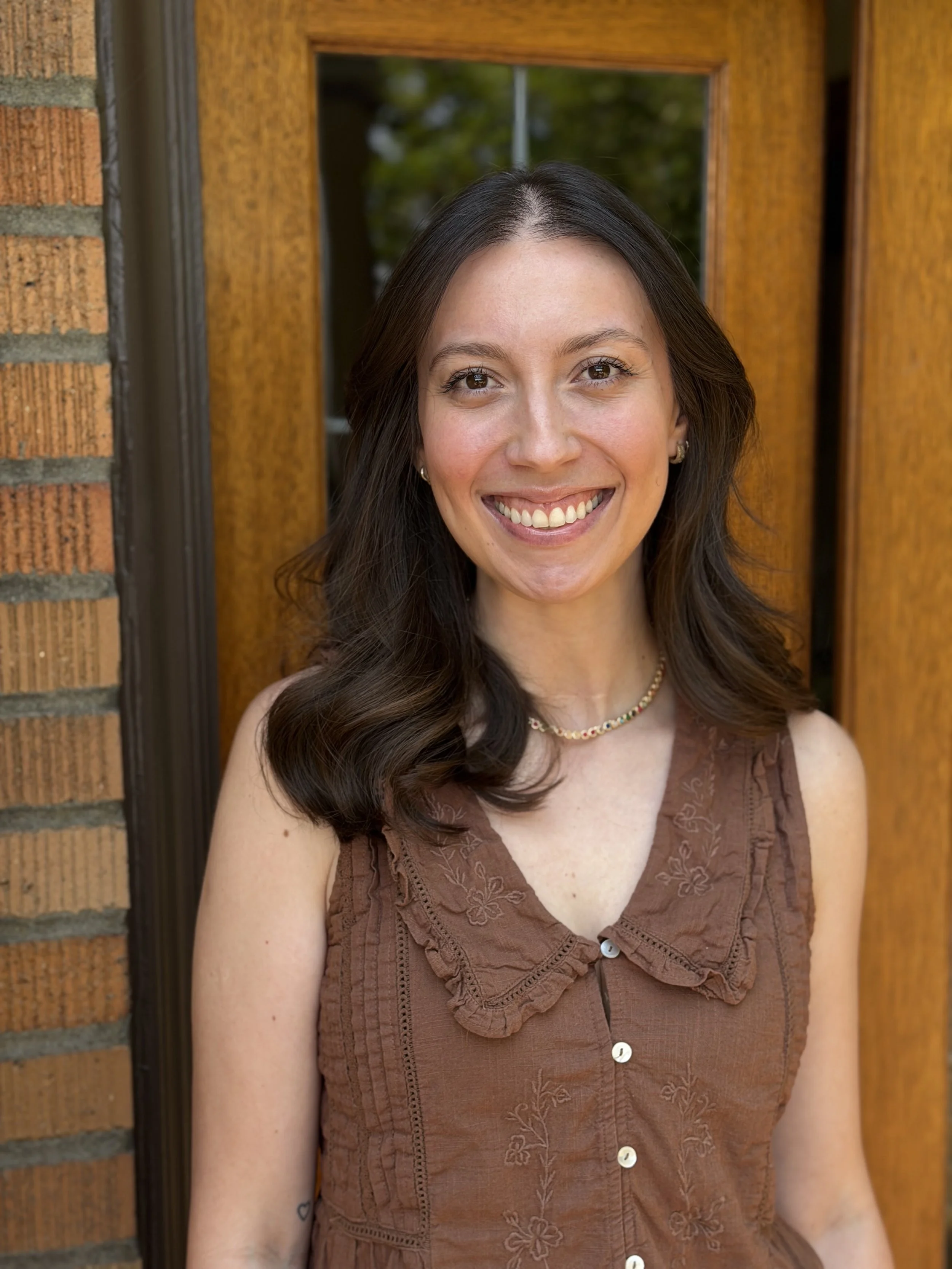 Smiling young woman with dark brown hair and a brown top