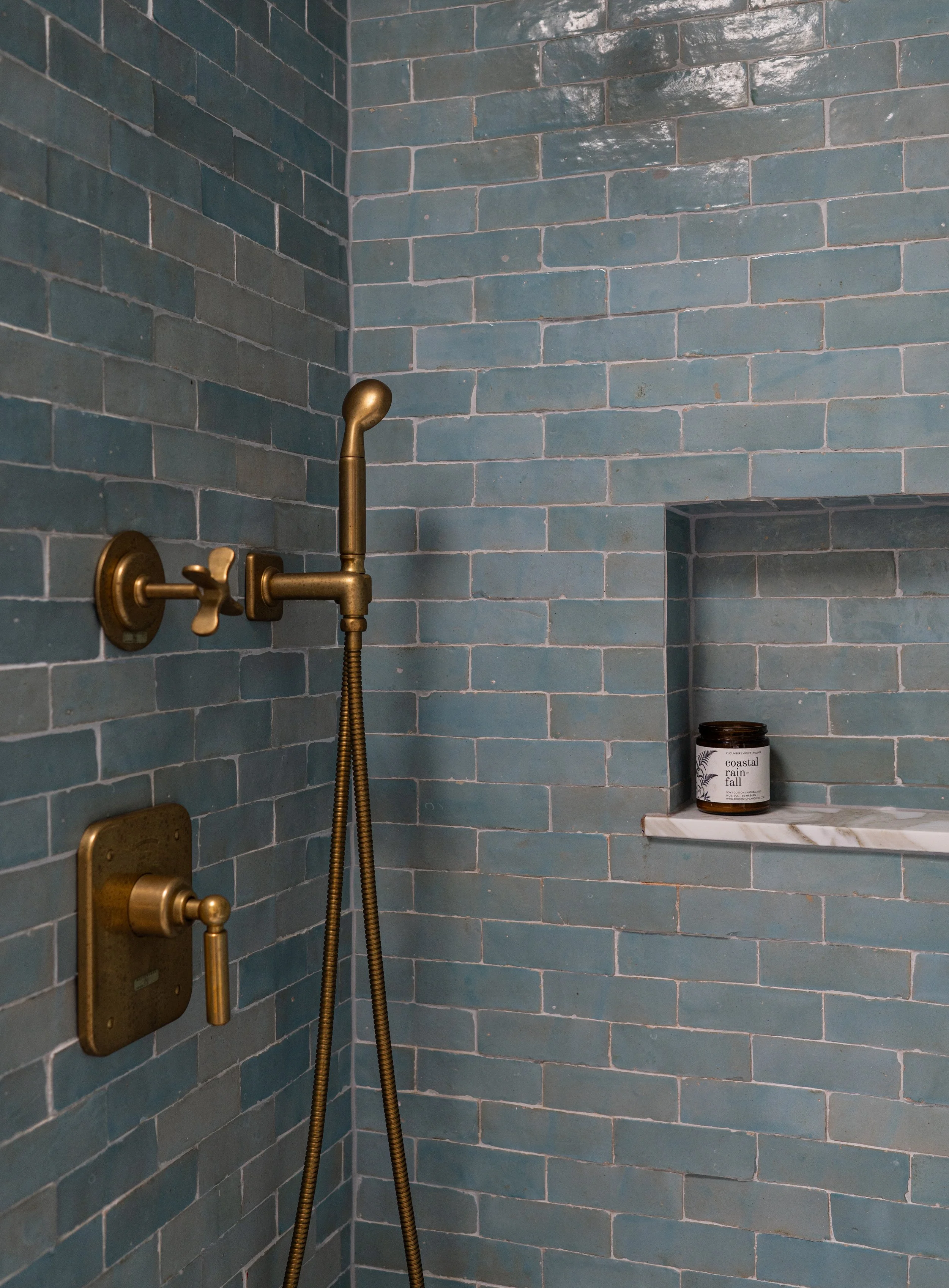 Blue tile walk-in shower with brass fixtures