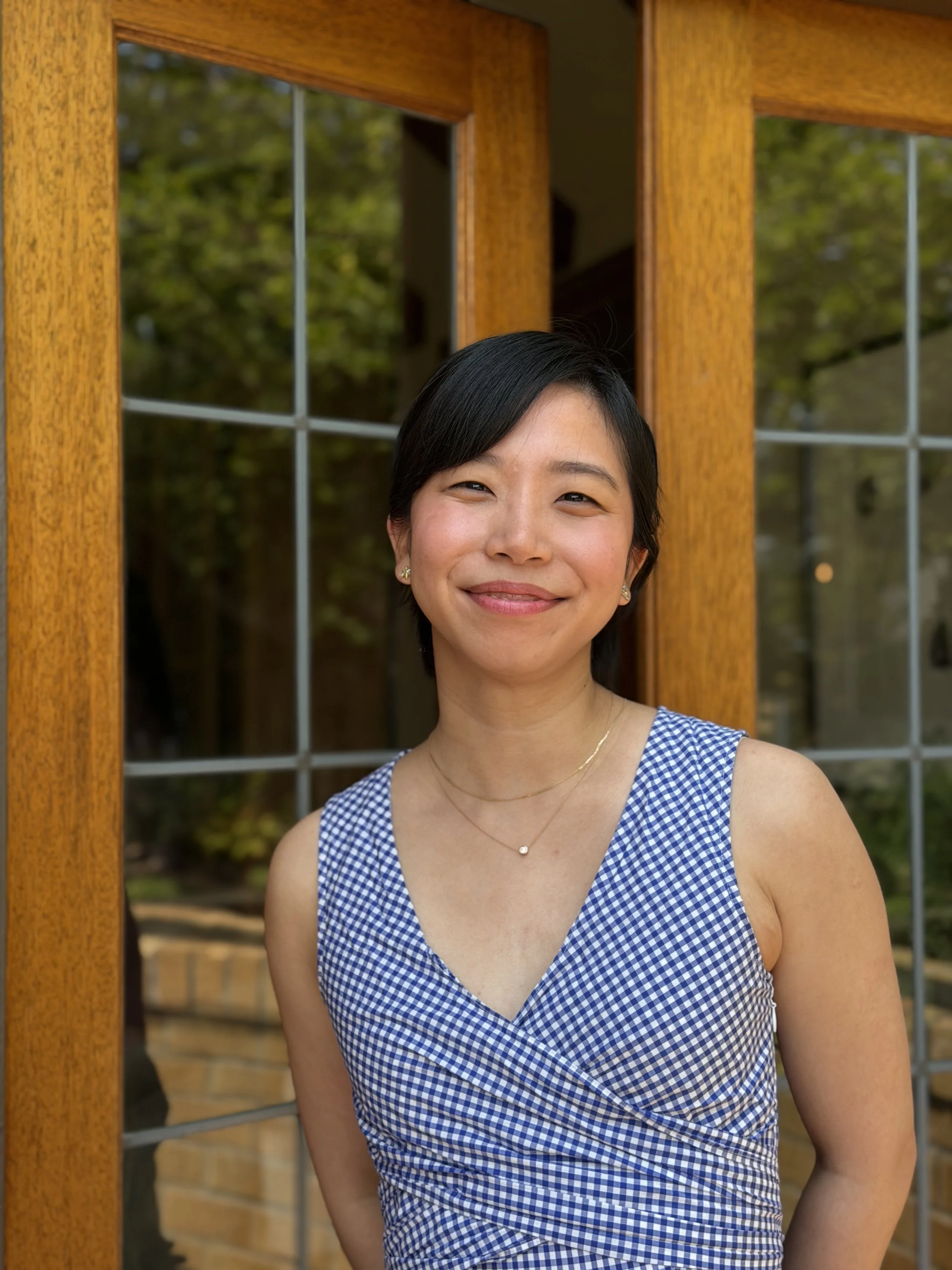 A young woman smiling with short black hair and blue top