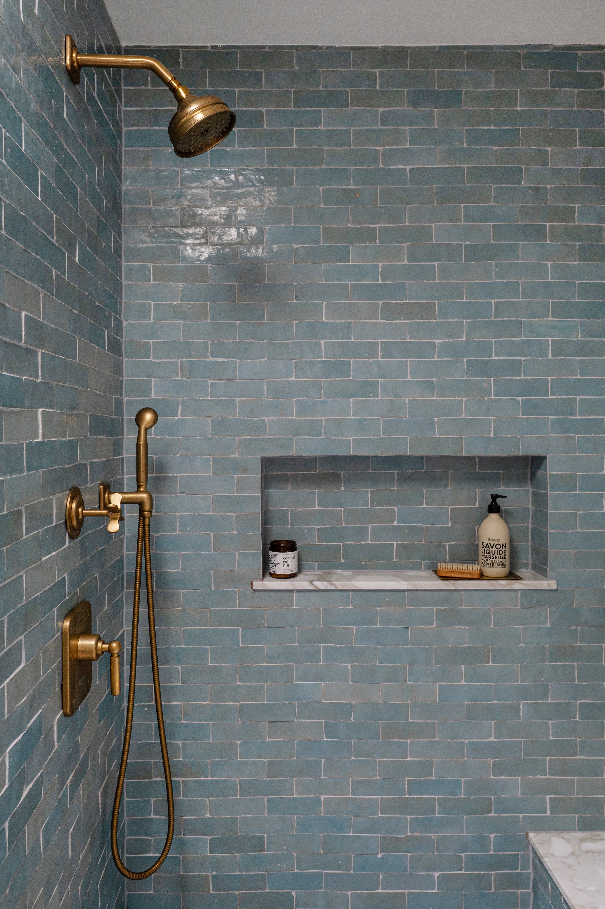 Blue tile walk-in shower with brass fixtures