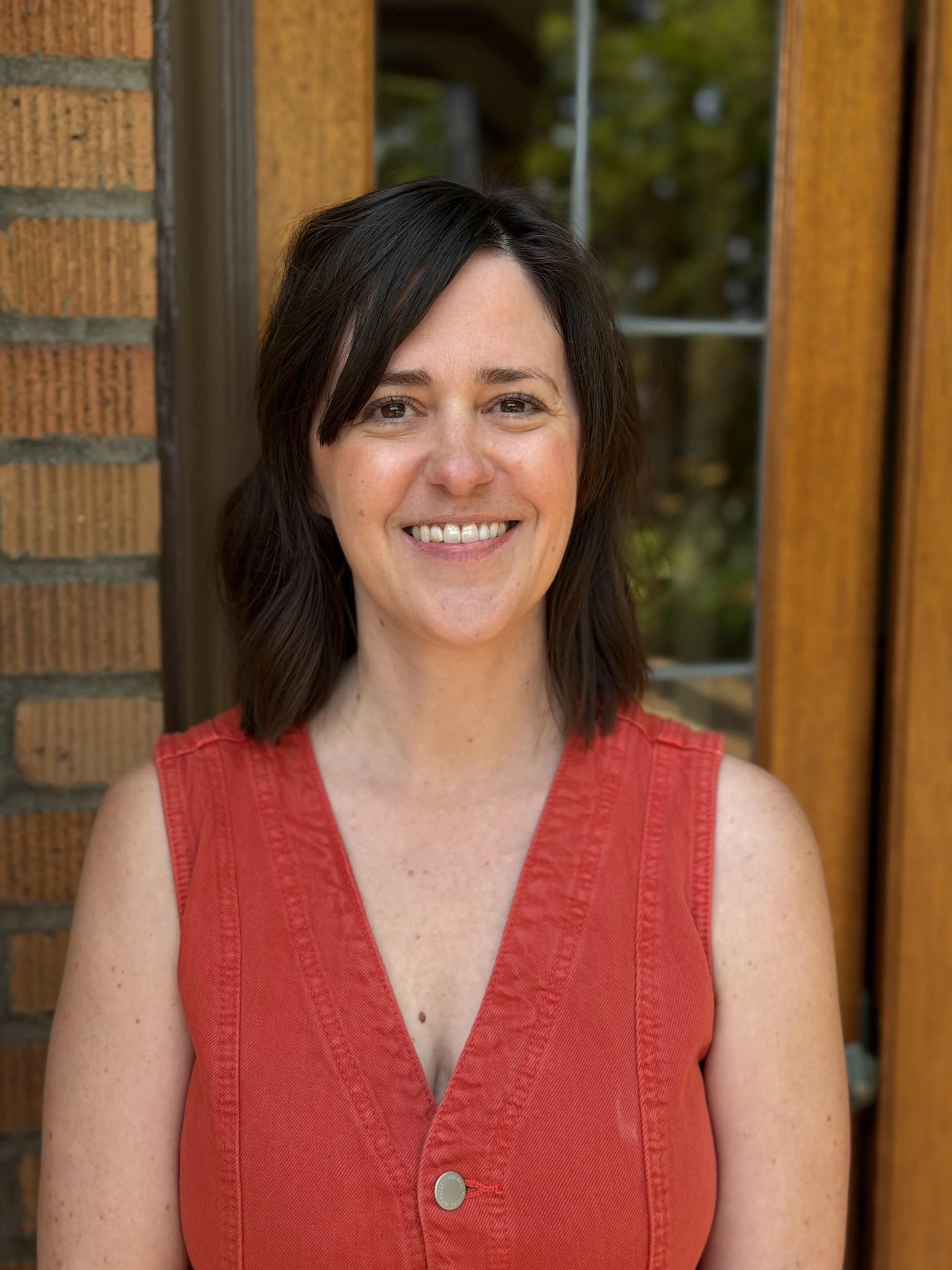 Woman with short brown hair in red vest