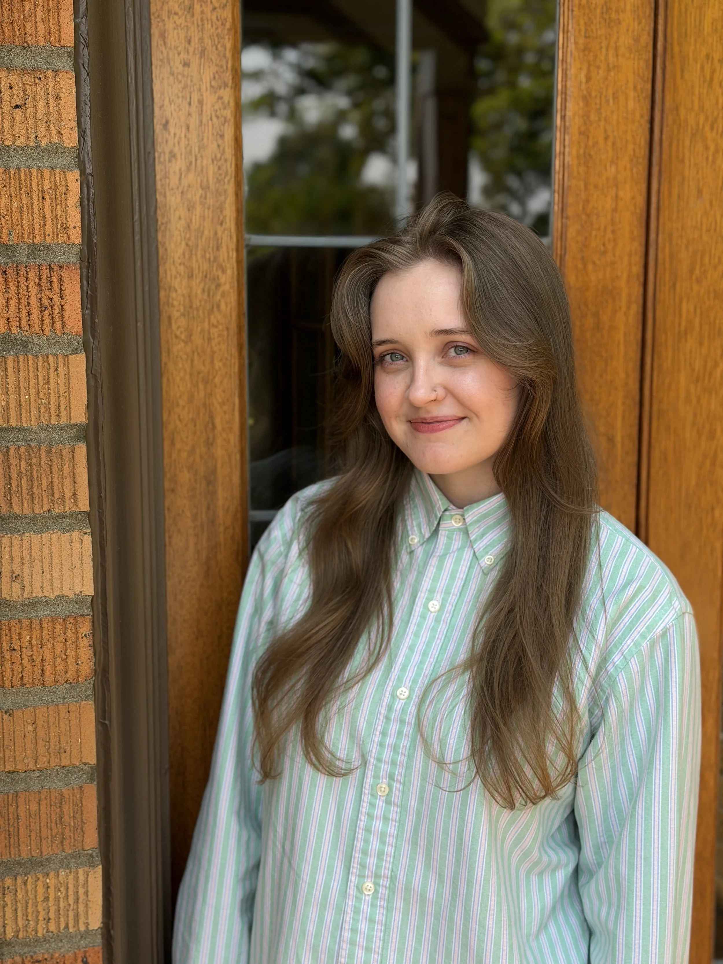 Smiling young brunette woman in striped green button-down
