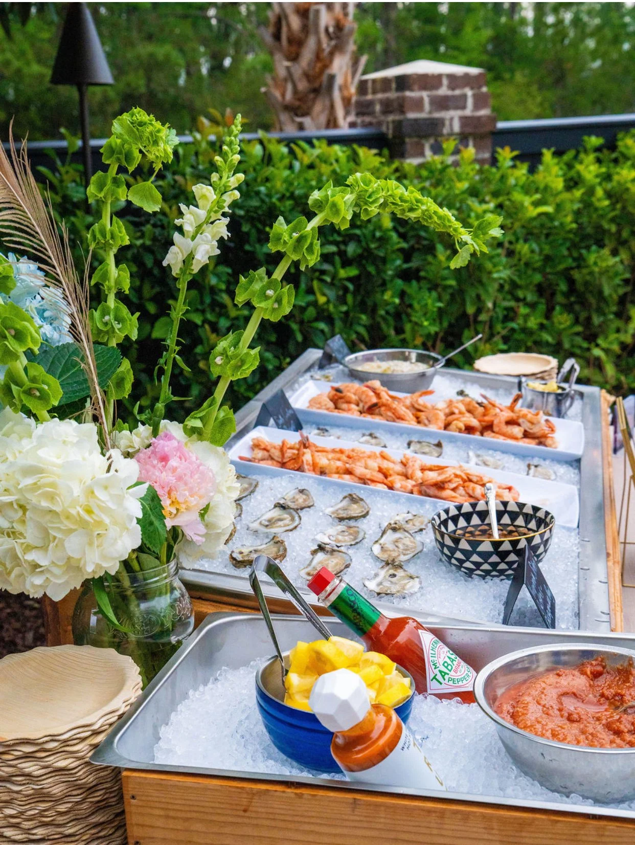 Styled Charleston raw bar with oysters, shrimp cocktail, florals, and coastal private event catering by Sweet Mae's.