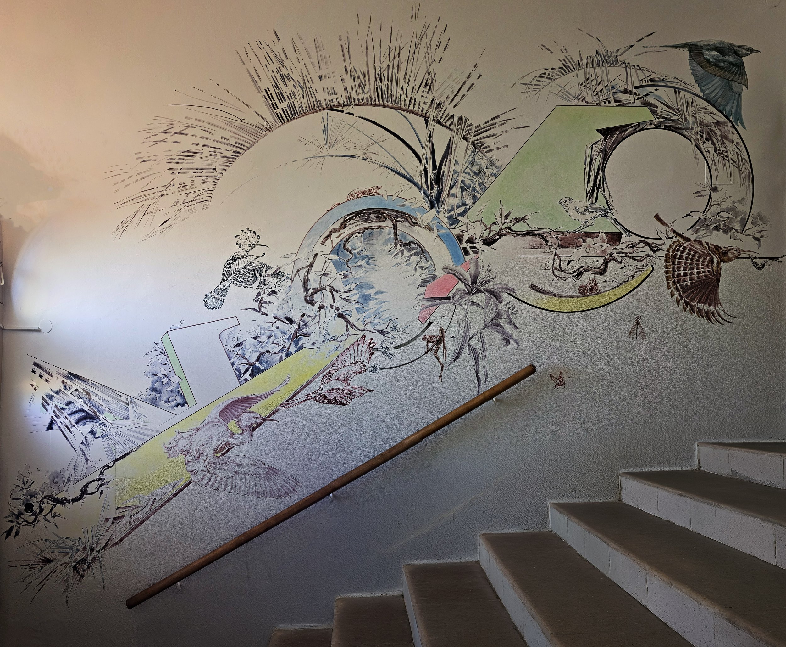 Das Bild zeigt eine leichte aber dynamische Komposition mit verschiedenen Elementen aus Fauna und Flora. Das Wandbild spielt mit dem Lichteinfall und den Art Deco Elementen des Gebäudes. Farblich bindet es die bunten Glassfenster des Eingangsportals