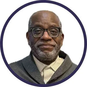 A black man wearing glasses and a grey sweater, looking directly at the camera with a neutral expression..jpg