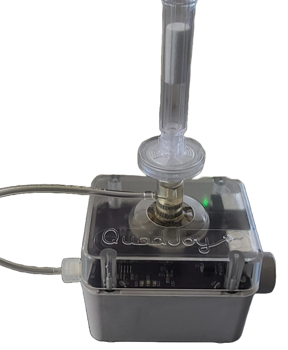 A white lab device called QuadJoy with a clear glass tube attached, connected to tubing and electronic components inside the device, with a green indicator light on.