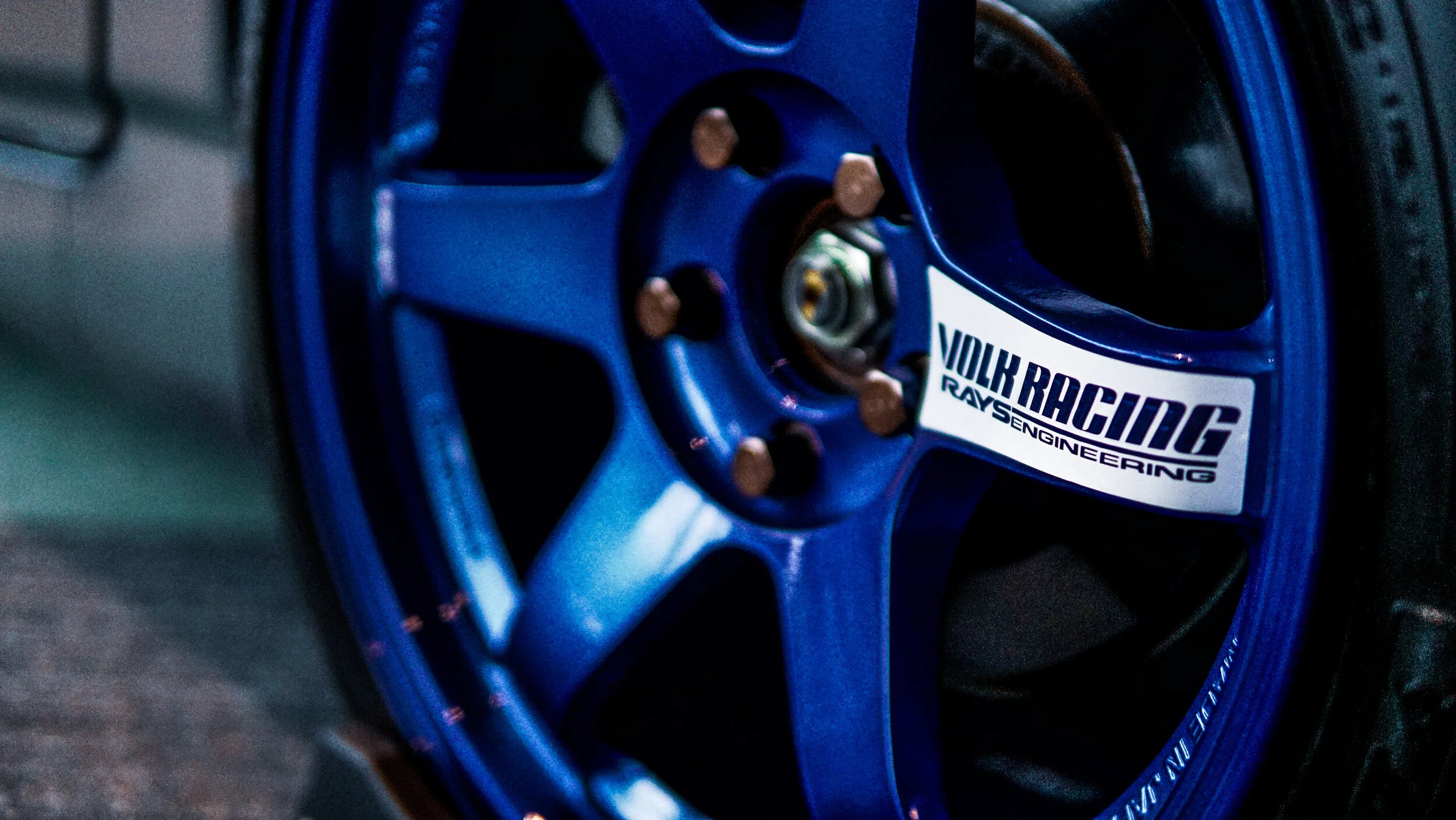 Close-up of a blue racing wheel with a sticker that reads 'Volks Racing Ray S Engineering'.