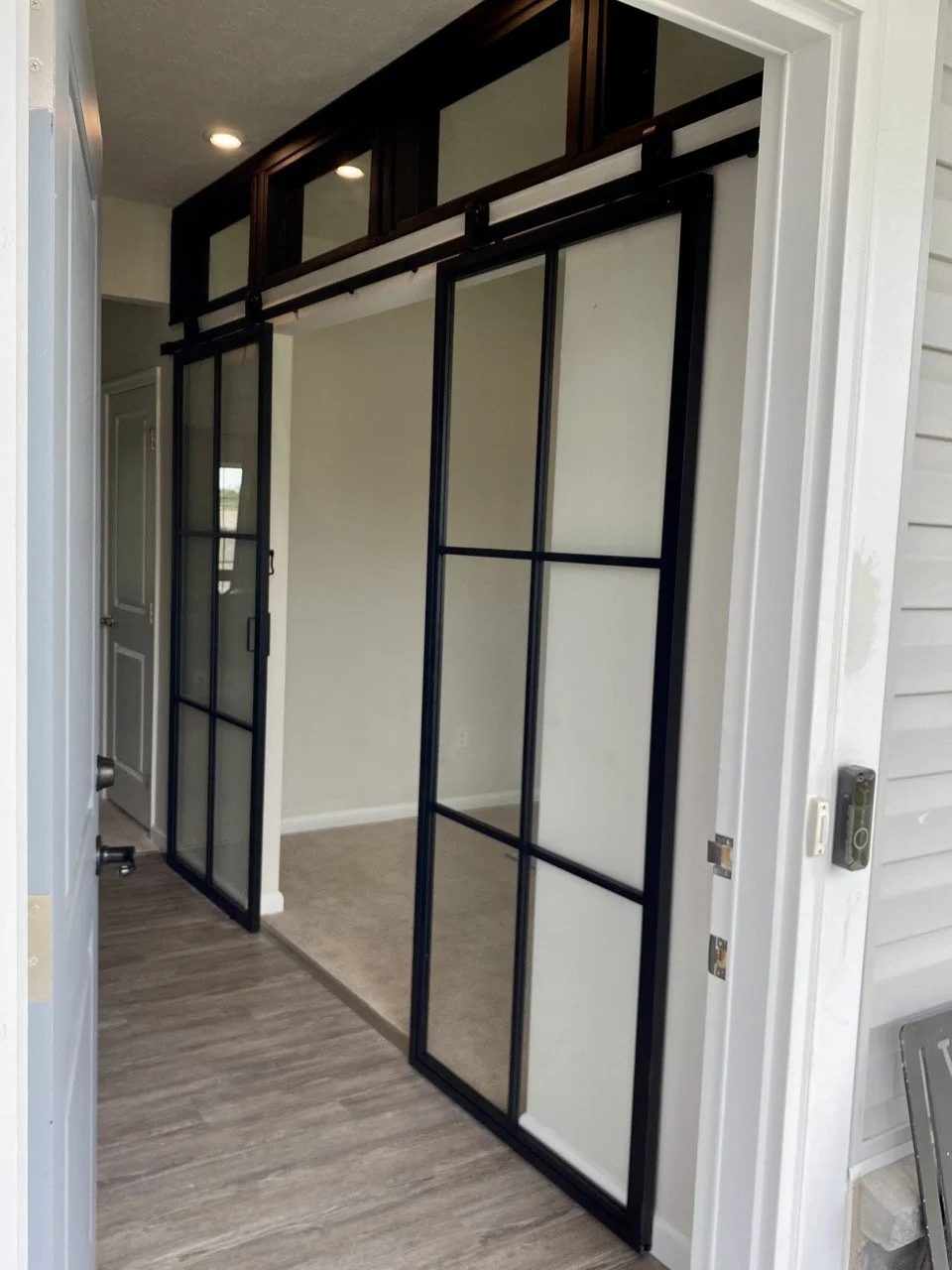 photo of a partition wall installation, closing off an office space with custom transom windows and black trim glass barn door