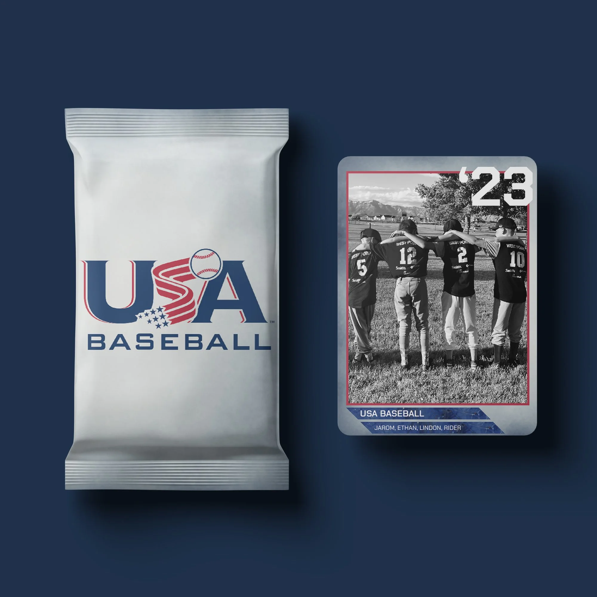 A USA Baseball trading card featuring four players in black and white, standing outdoors on a grassy field with their arms around each other, and a pack of USA Baseball trading cards with a baseball-themed logo on the left.